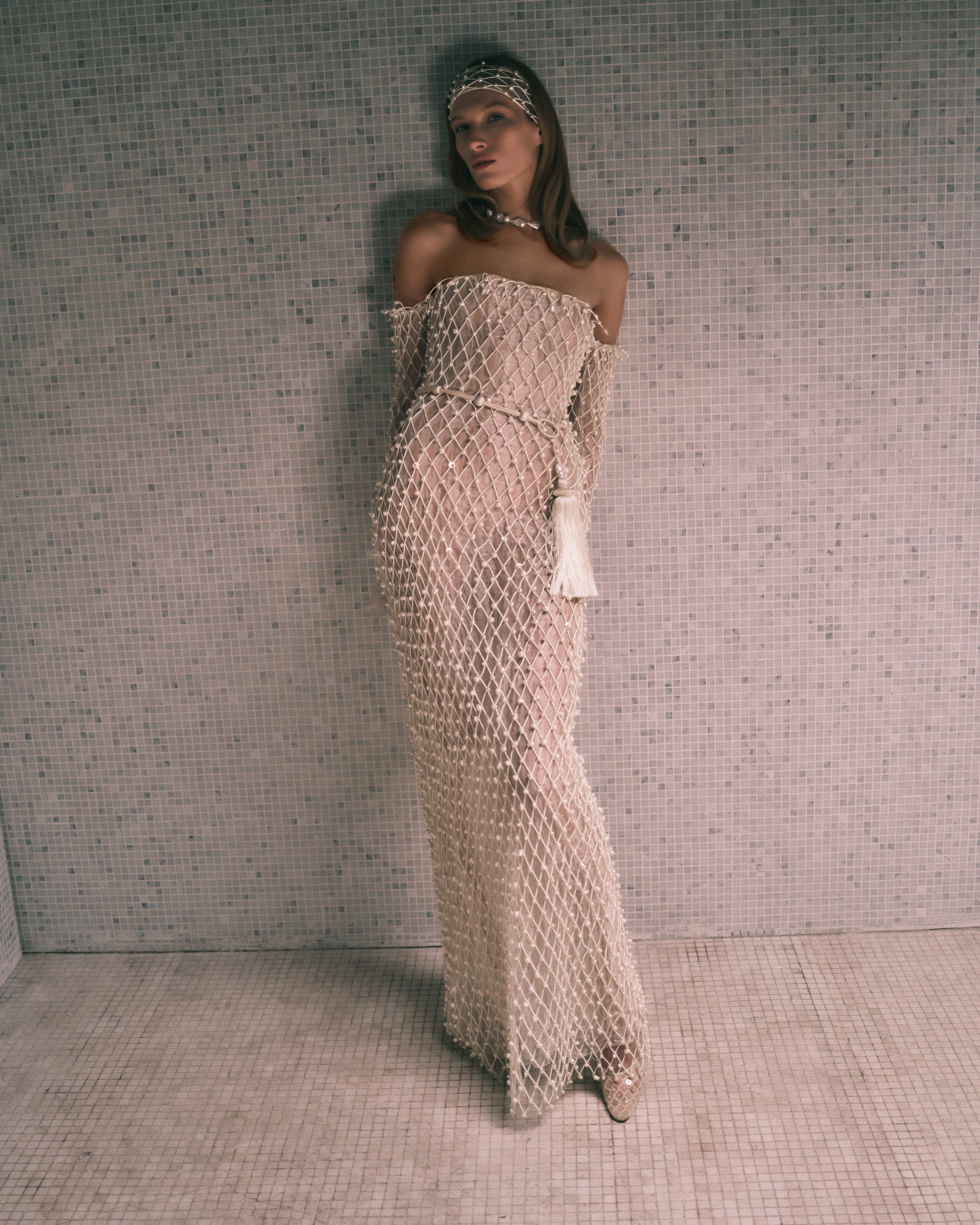 Warped transparent organza off the shoulder column gown with hand applied corded trellis embroidery embellished in transparent sequins and baroque pearls. Fringe hem detail at sleeves is finished with genuine teardrop pearls. Bobinette lining with boned internal bustier. Invisible zip closure at center back.