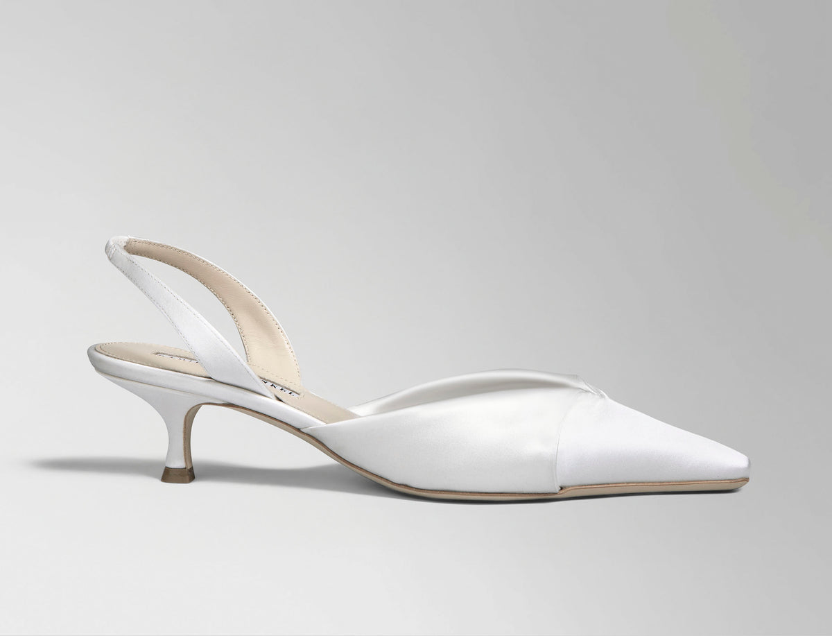 Rounded square toe sling back crafted in Italy of ivory satin. Sculpted satin detail peels away at neckline as it wraps around the foot. 50mm kitten heel.