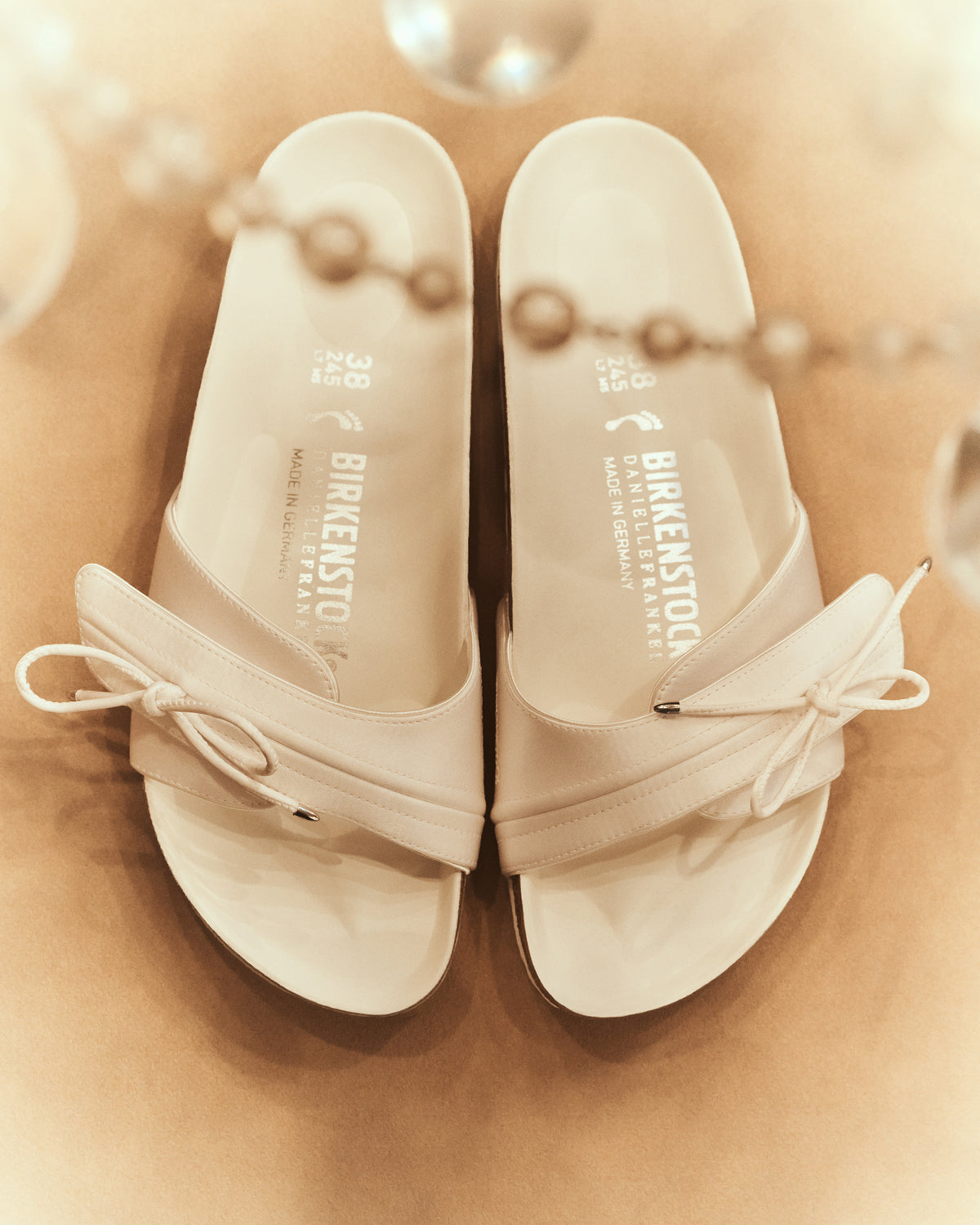BIRKENSTOCK’s original 1963 design is reimagined by Danielle Frankel in a pure, minimalist silhouette with a delicate satin upper. A satin cord with metal-tipped ends adds refined elegance. The design also introduces an innovative adjustable hidden buckle closure, while handcrafted German craftsmanship ensures the iconic comfort and quality BIRKENSTOCK is known for. - Upper: Delicate satin upper, bow detail with metal ends- Footbed: Anatomical shaped BIRKENSTOCK cork latex Footbed lined with premium Nappa Leather- Sole: EVA die cut outsole with a custom design, blending classic BIRKENSTOCK bone pattern with delicate leaf inspired detailing