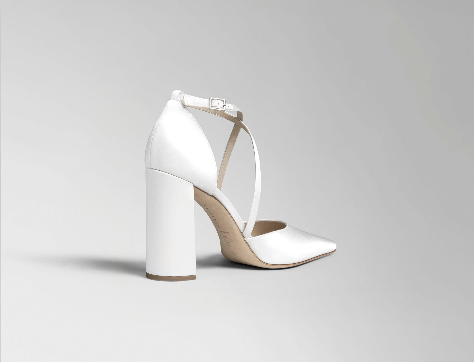 Classic rounded square toe pump with criss cross ankle strap, crafted in Italy of ivory satin. 100mm block heel.