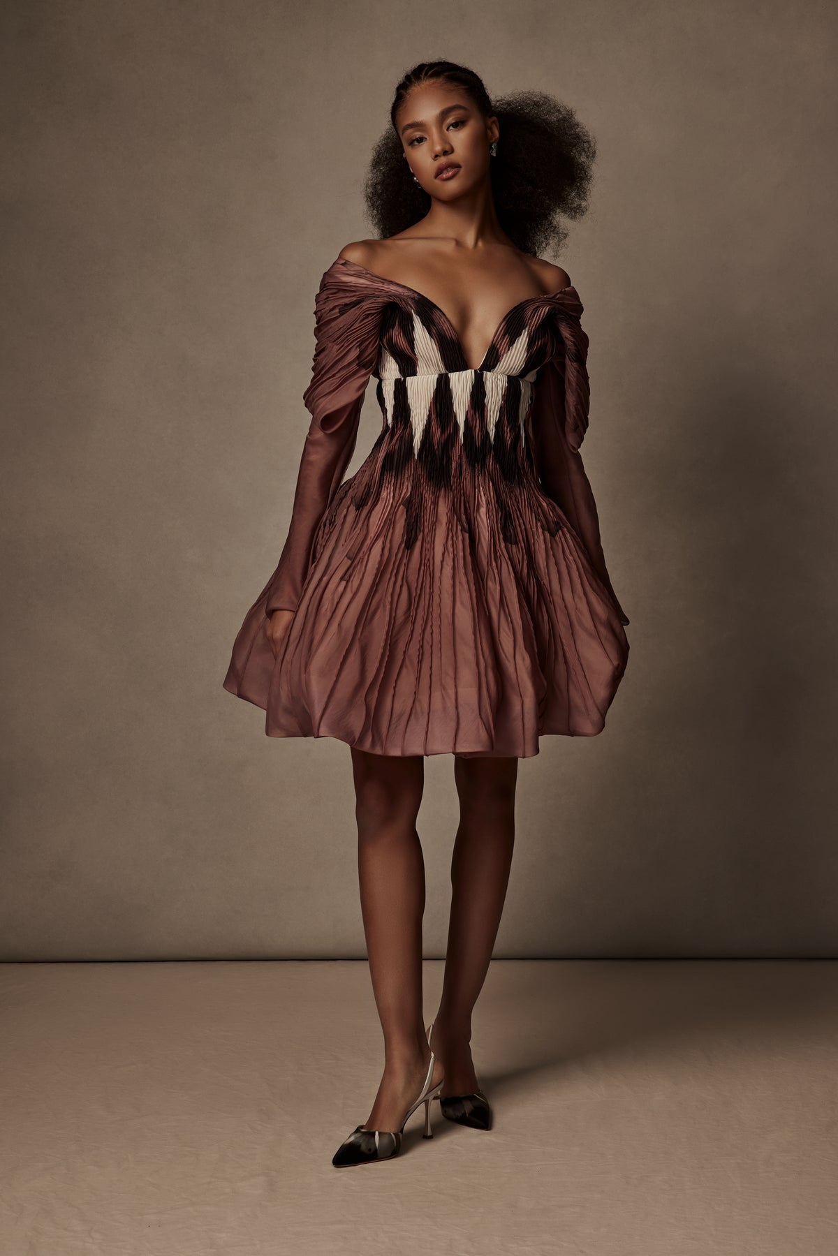 Sculpted foggy organdy mini dress. Draped and hand pintucked v-neckline with sheer, long sleeve. Gathered and tacked bubbled crinoline skirt. Boning through body and center back zip close.
