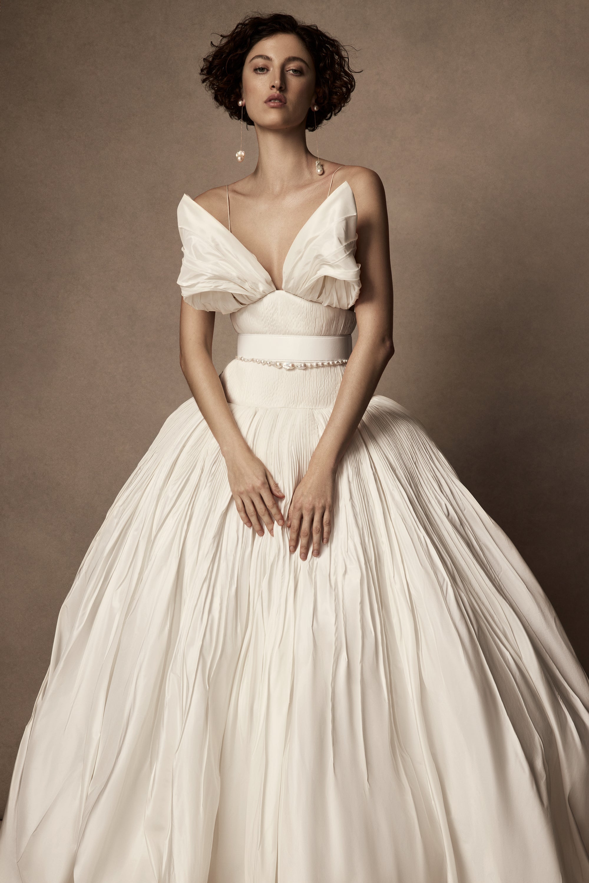 Micro-tucked silk taffeta ballgown. Crinoline enclosed, bubbled skirt with extended train. Soft triangular cups for support beneath abstract triangular draped taffeta panels. Soft boning for structure and center back close. The belt is sold separately.