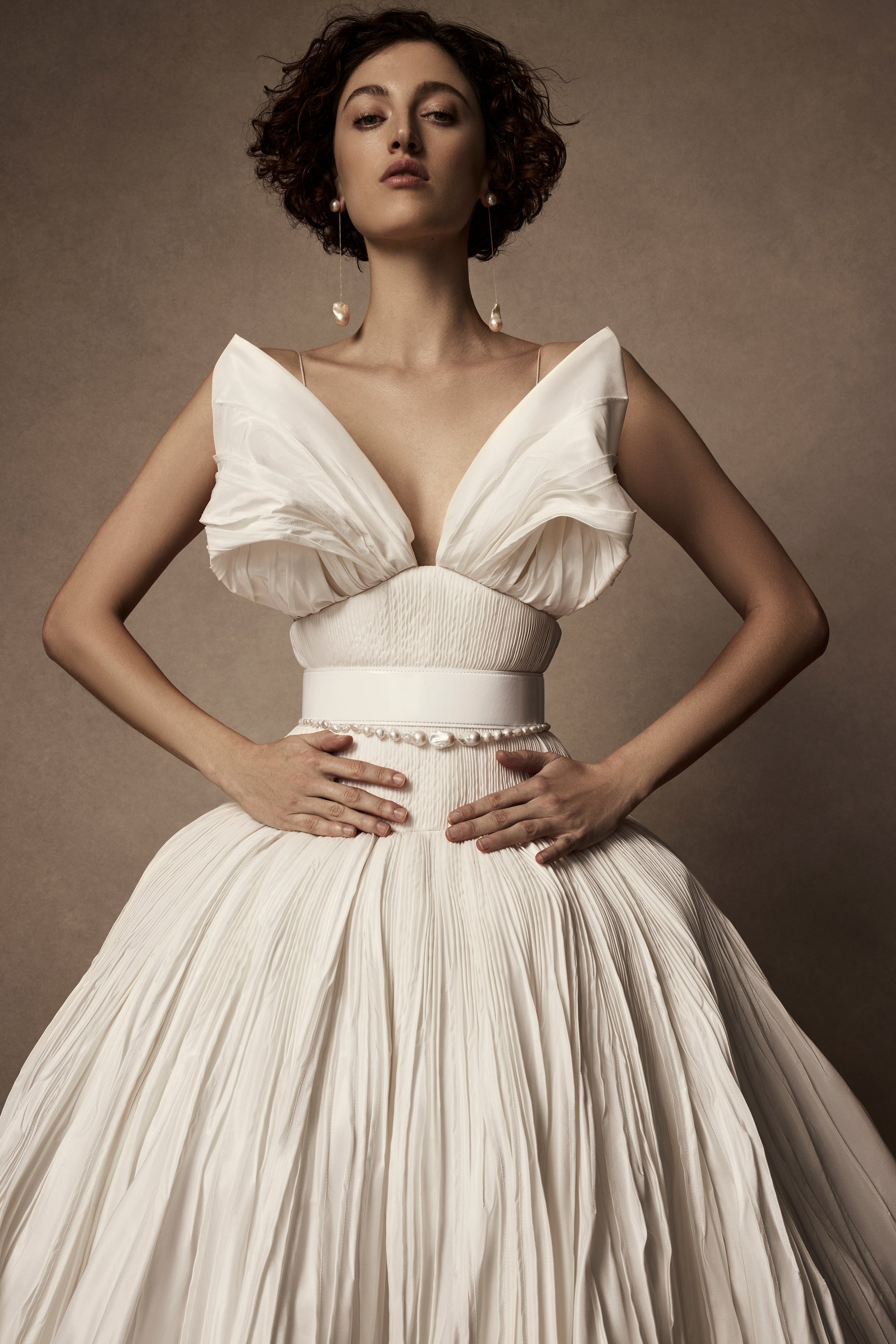 Micro-tucked silk taffeta ballgown. Crinoline enclosed, bubbled skirt with extended train. Soft triangular cups for support beneath abstract triangular draped taffeta panels. Soft boning for structure and center back close. The belt is sold separately.