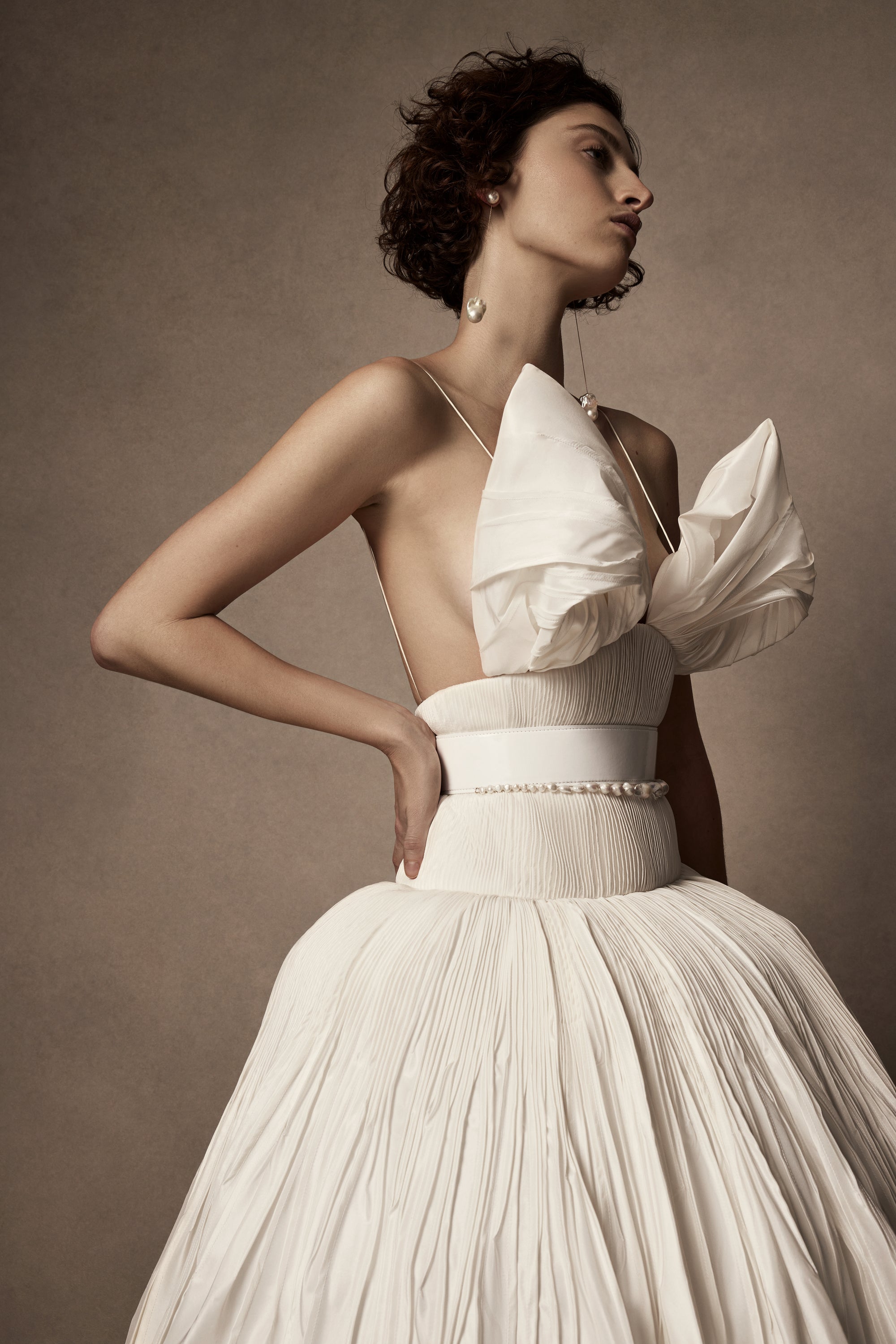 Micro-tucked silk taffeta ballgown. Crinoline enclosed, bubbled skirt with extended train. Soft triangular cups for support beneath abstract triangular draped taffeta panels. Soft boning for structure and center back close. The belt is sold separately.