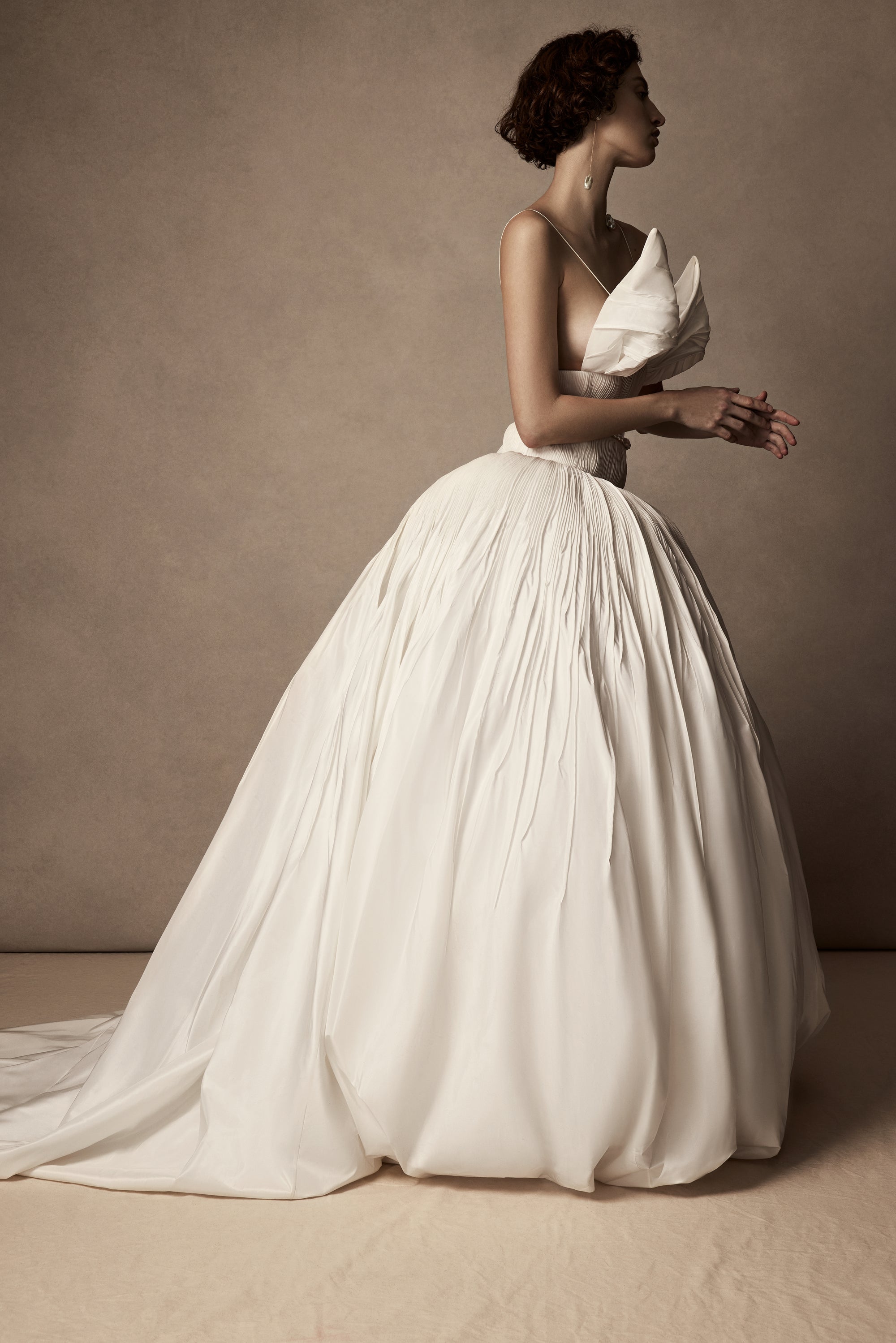 Micro-tucked silk taffeta ballgown. Crinoline enclosed, bubbled skirt with extended train. Soft triangular cups for support beneath abstract triangular draped taffeta panels. Soft boning for structure and center back close. The belt is sold separately.