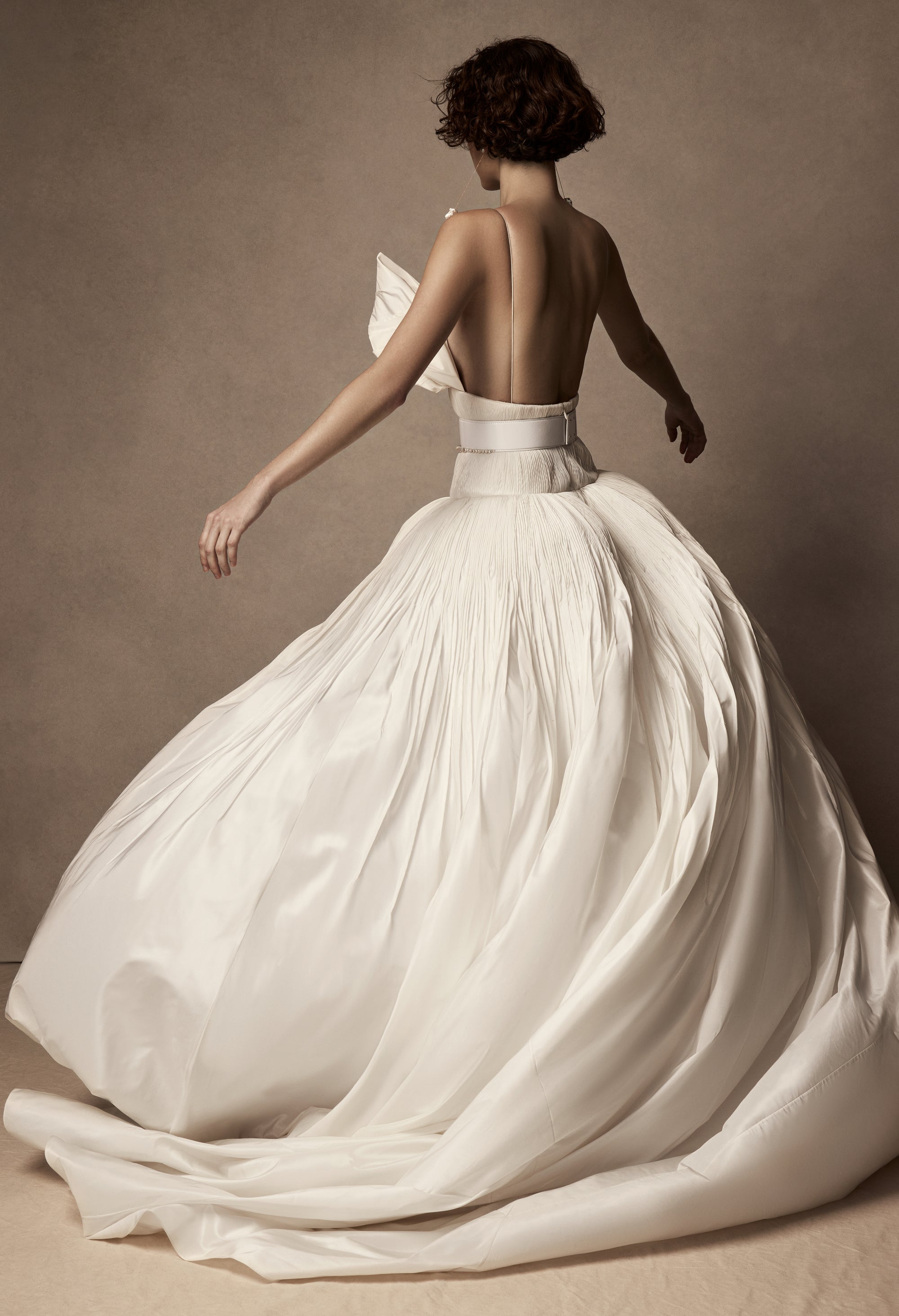 Micro-tucked silk taffeta ballgown. Crinoline enclosed, bubbled skirt with extended train. Soft triangular cups for support beneath abstract triangular draped taffeta panels. Soft boning for structure and center back close. The belt is sold separately.