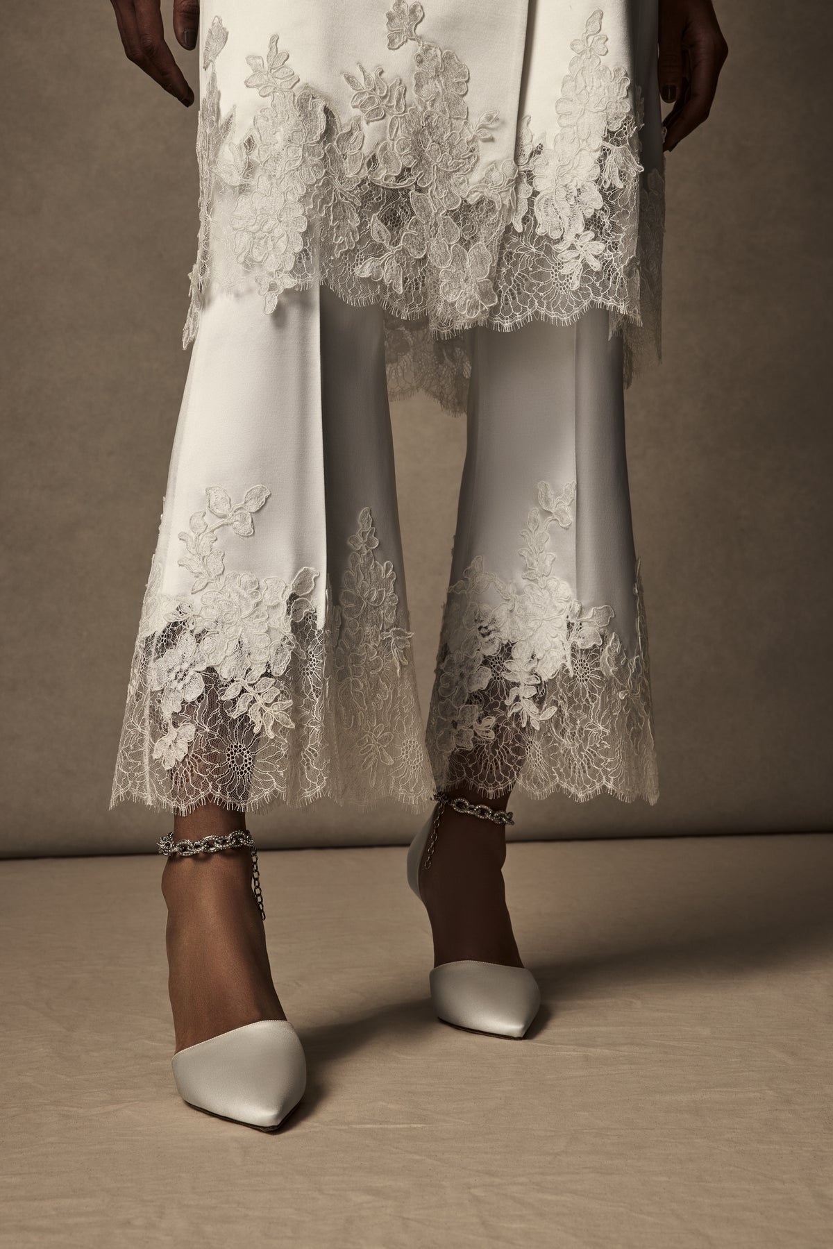Double breasted lace mended midi overcoat. Silk wool body with peaked lapels and flap pocket accent at hips. Hand cut appliqués ornamented along lace cuffs and hemline. Shoulder pads for structure and button close.