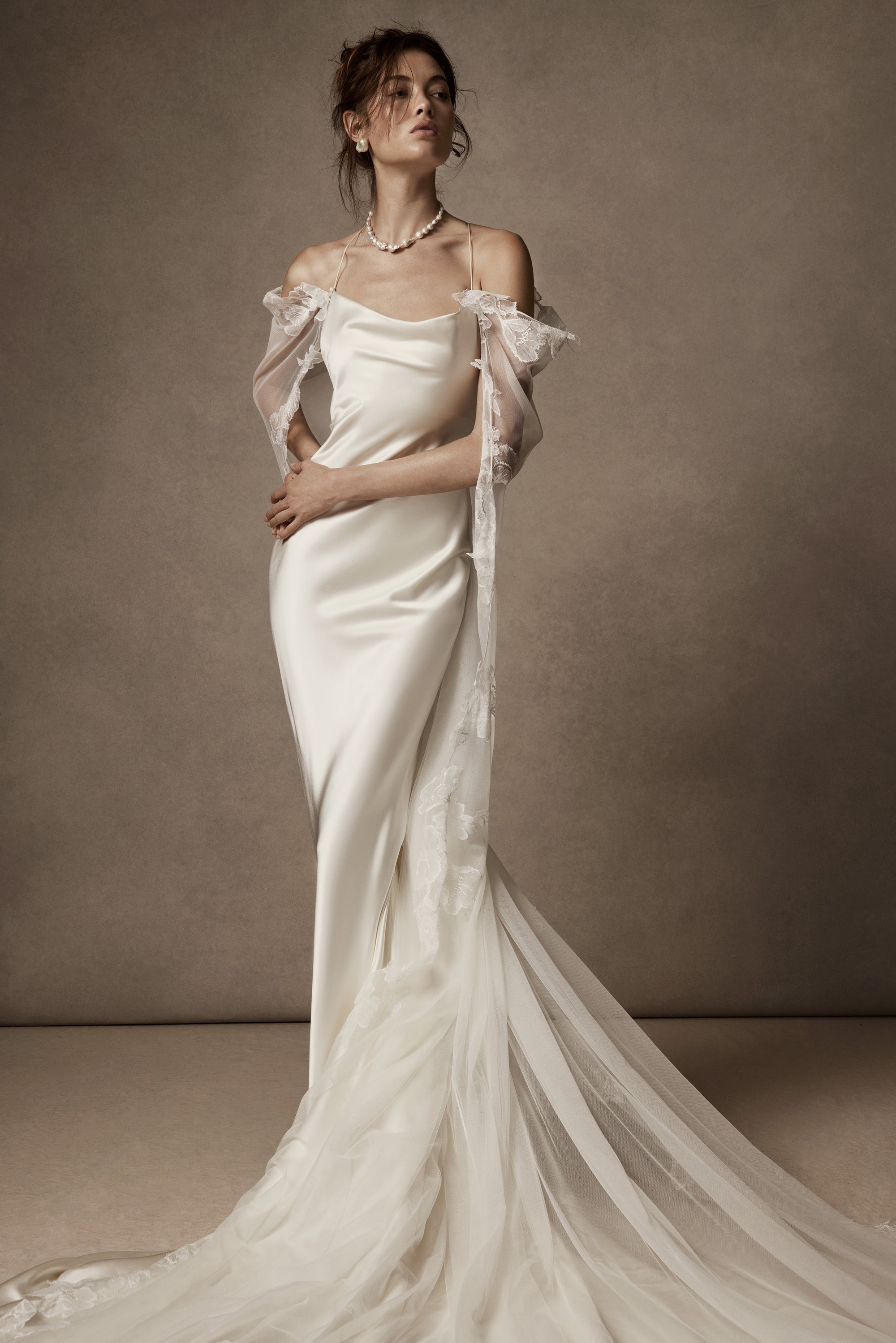 Cowled neck, crepe back satin slip gown. Low scooped back with cross back spaghetti straps. Detachable tulle cape with hand appliquéd chantilly lace edging along sides. Center back zip, hook and eye closure.