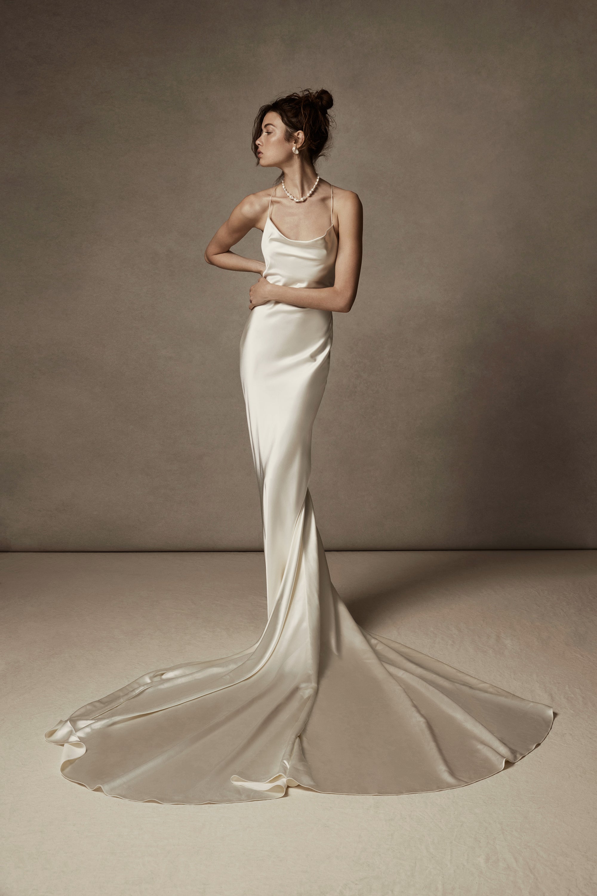 Cowled neck, crepe back satin slip gown. Low scooped back with cross back spaghetti straps. Detachable tulle cape with hand appliquéd chantilly lace edging along sides. Center back zip, hook and eye closure.