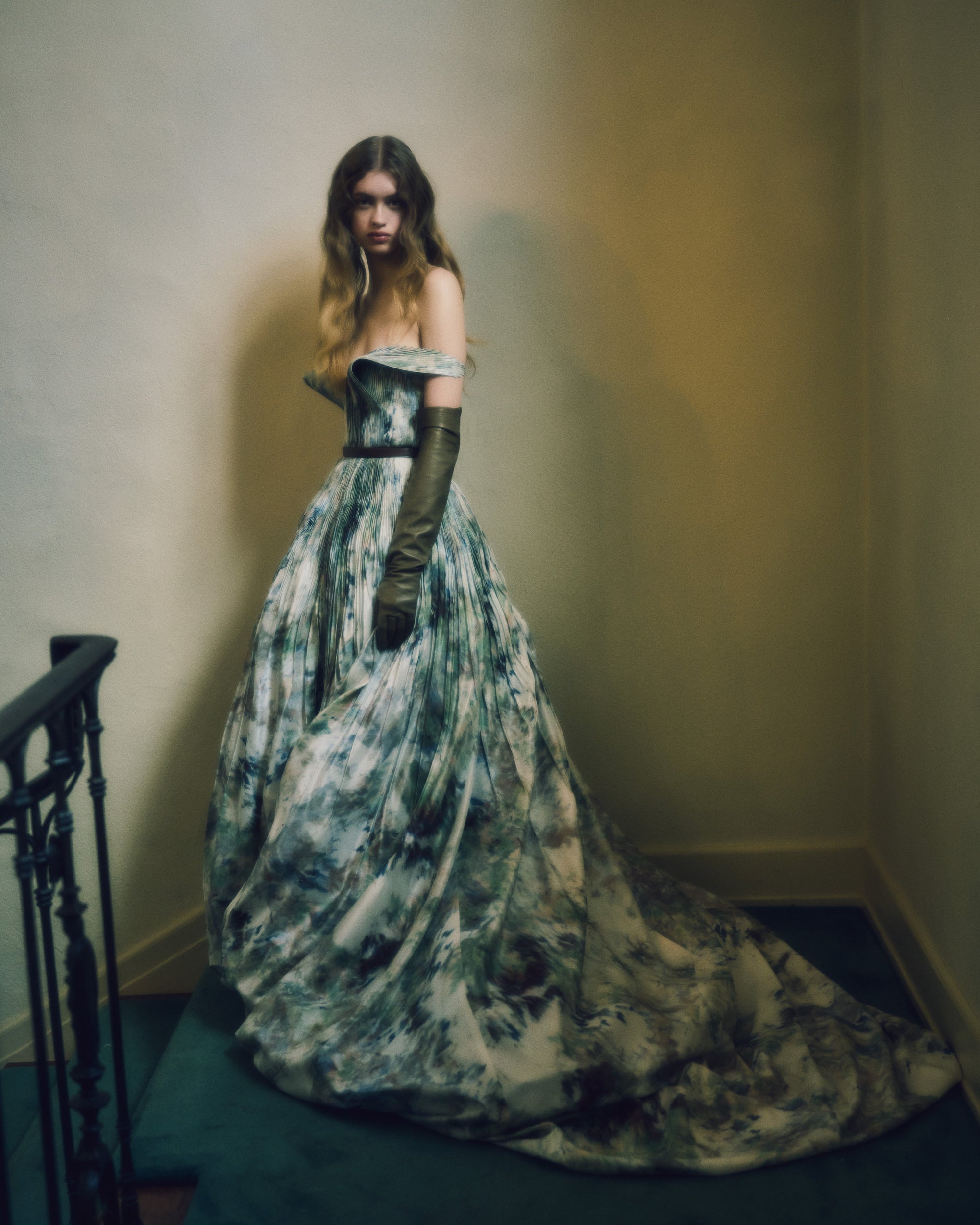 Hand tucked silk taffeta off the shoulder gown with piqued bust and dramatic bubbled skirt and train. Pin tucked panels drape delicately over arms and secure with a spaghetti tie at back. Boned internal bustier, internal grosgrain waist belt and center back zip closure.