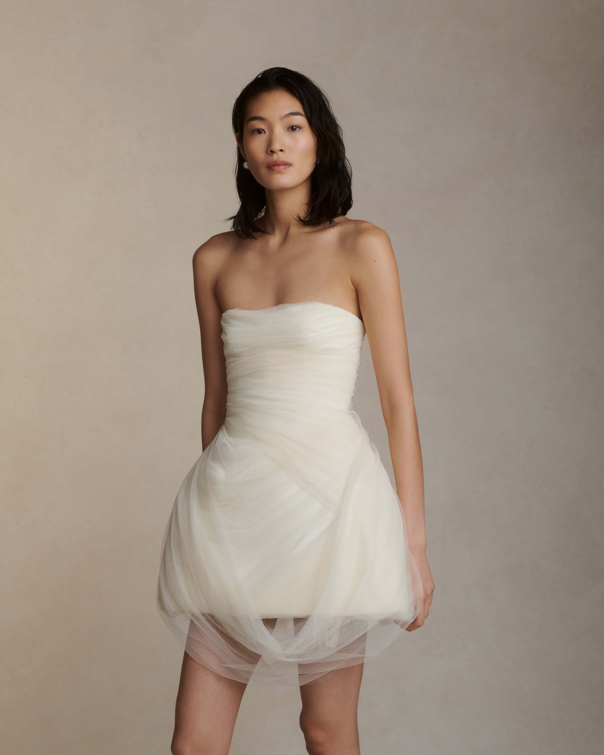 Strapless structured Cady mini dress with draped soft tulle overlay. Layers of tulle draping cascade into a swagged front skirt and dip at back to reveal boned organza bustier. Center back zip closure.