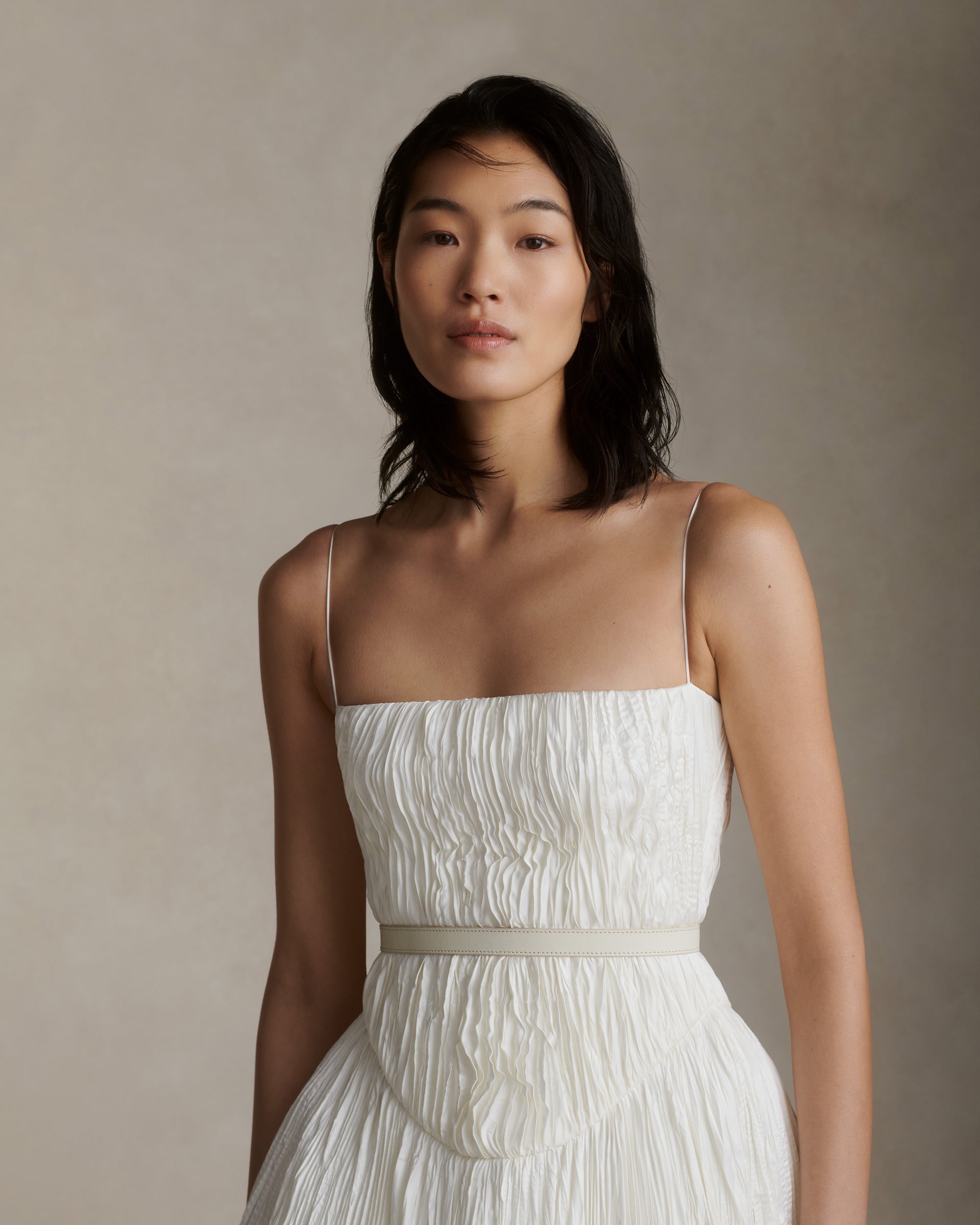 Pleated satin, bubbled and collapsed soft crinoline ball gown. Horse hair for skirt shaping and hand tacking across waist and under bust for shaping. Soft internal corset with boning and grosgrain accent belt with three position closure. Center back heavy duty zipper closure.