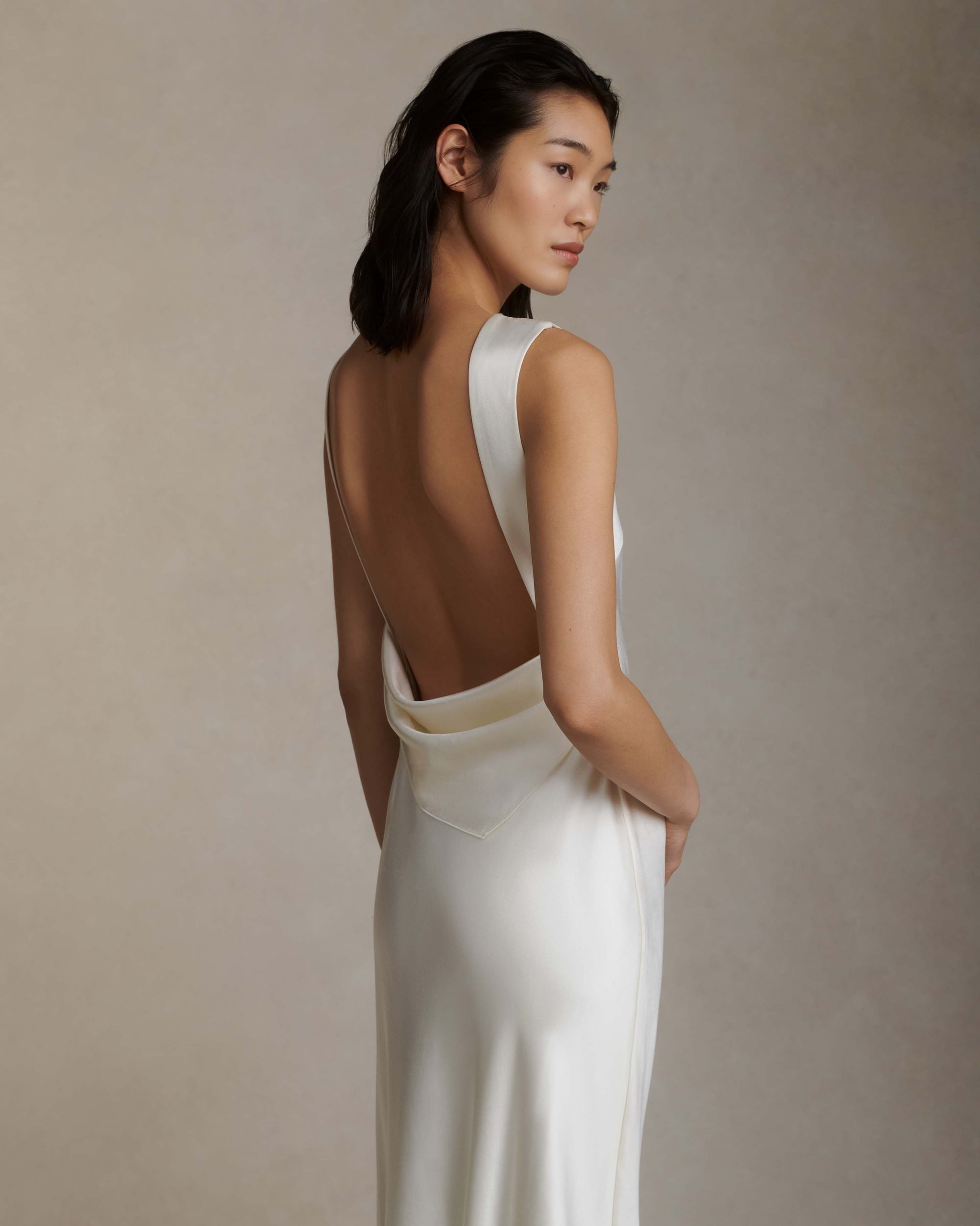 Raised cowl neck, bias cut silk wool sleeveless gown. Open back with scarf draped accent. Fully lined with side zip closure.Styled with Rebecca lace bolero