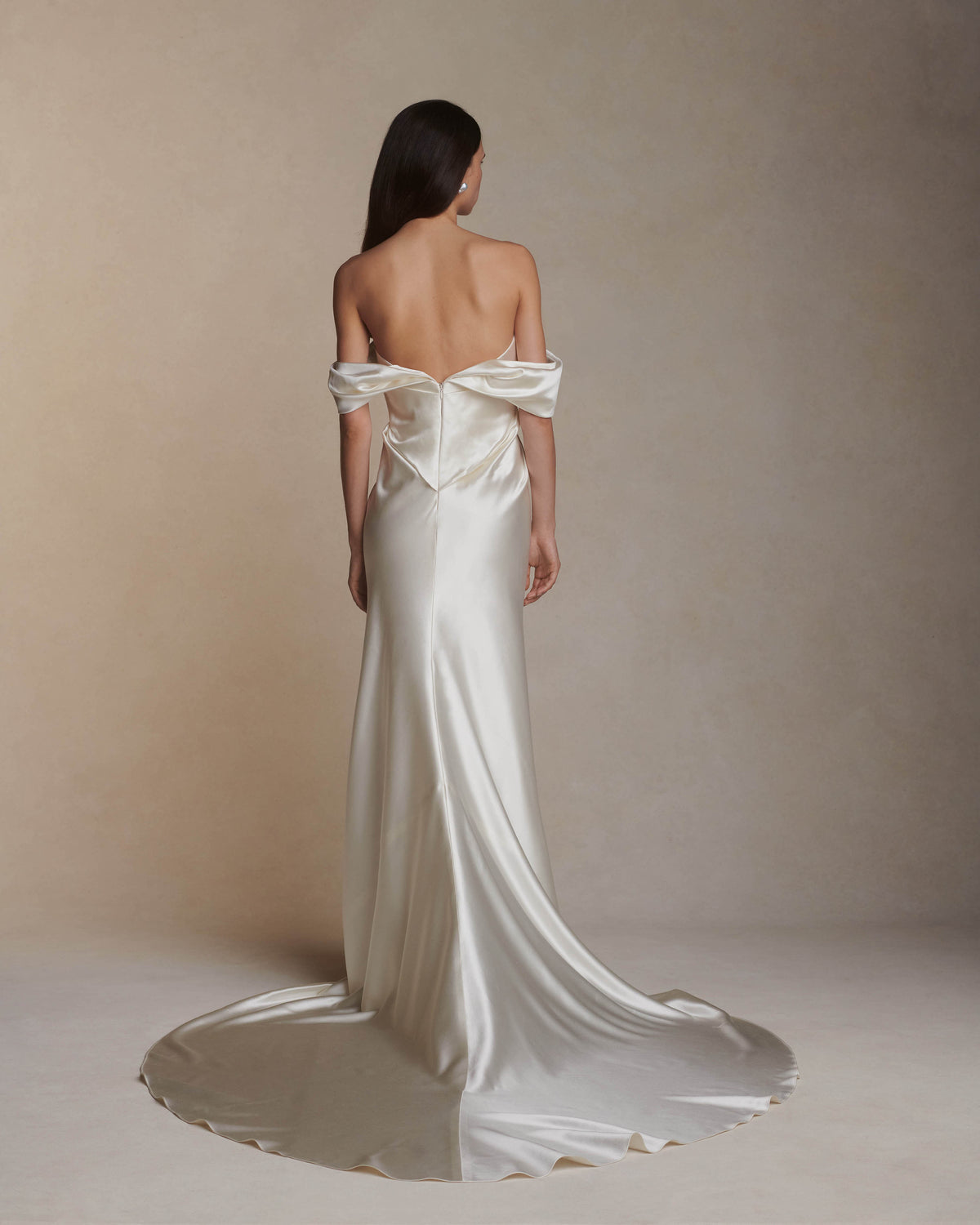 Off the shoulder silk wool gown with elegant draping at center front releasing into swagged sleeve detail. Boned internal bustier with soft cups, internal grosgrain waist belt and invisible side zip closure. 