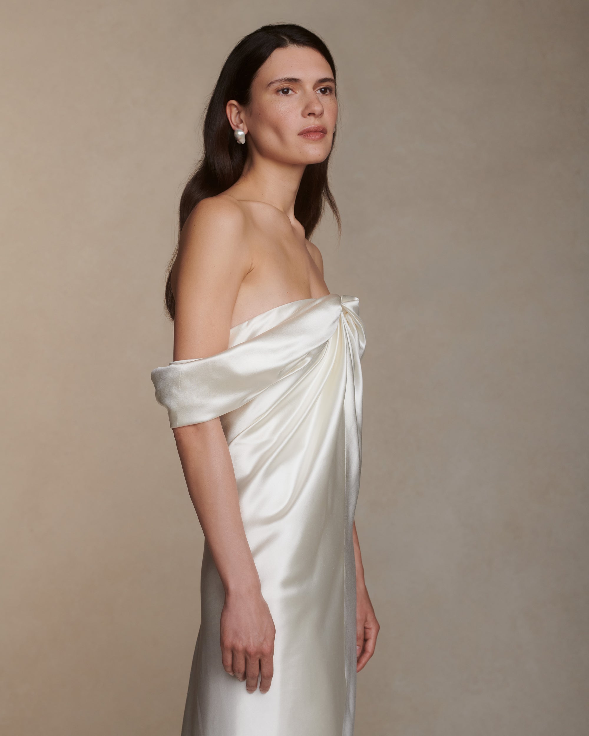 Off the shoulder silk wool gown with elegant draping at center front releasing into swagged sleeve detail. Boned internal bustier with soft cups, internal grosgrain waist belt and invisible side zip closure. 