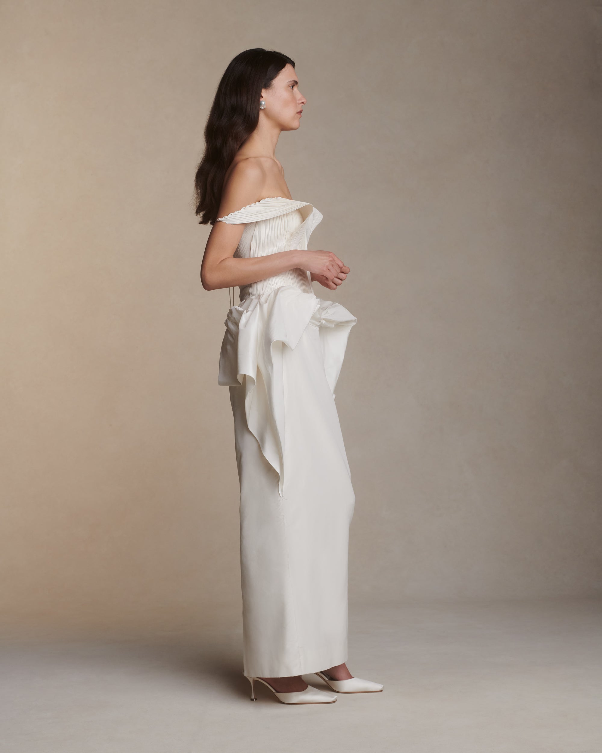 Structured hand tucked silk taffeta strapless dress with piqued bust, exaggerated waist drape and column skirt. Micro tucked panels drape delicately over arms and secure with a spaghetti tie at back. Boned internal bustier with soft cups, invisible center back zip closure.