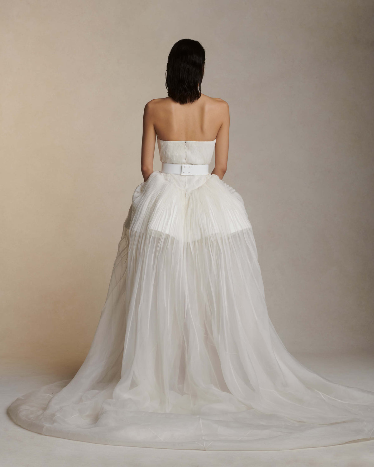 Silk organza strapless translucent ball gown with pintucked bodice. Basque waistline with soft sweetheart neckline. Sheer bubbled high-low skirt with extended train. Internal bustier with side boning and cups, grosgrain belt with 3 hook position. Center back zip close.The belt is sold separately.