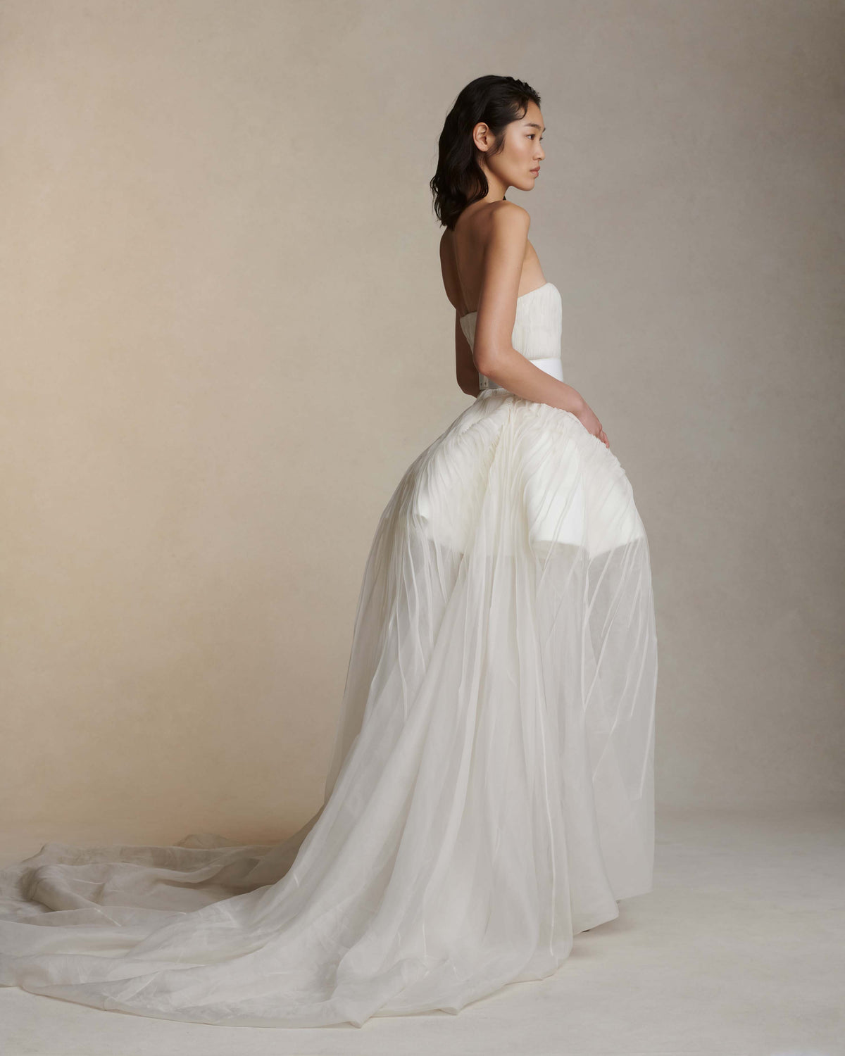 Silk organza strapless translucent ball gown with pintucked bodice. Basque waistline with soft sweetheart neckline. Sheer bubbled high-low skirt with extended train. Internal bustier with side boning and cups, grosgrain belt with 3 hook position. Center back zip close.The belt is sold separately.