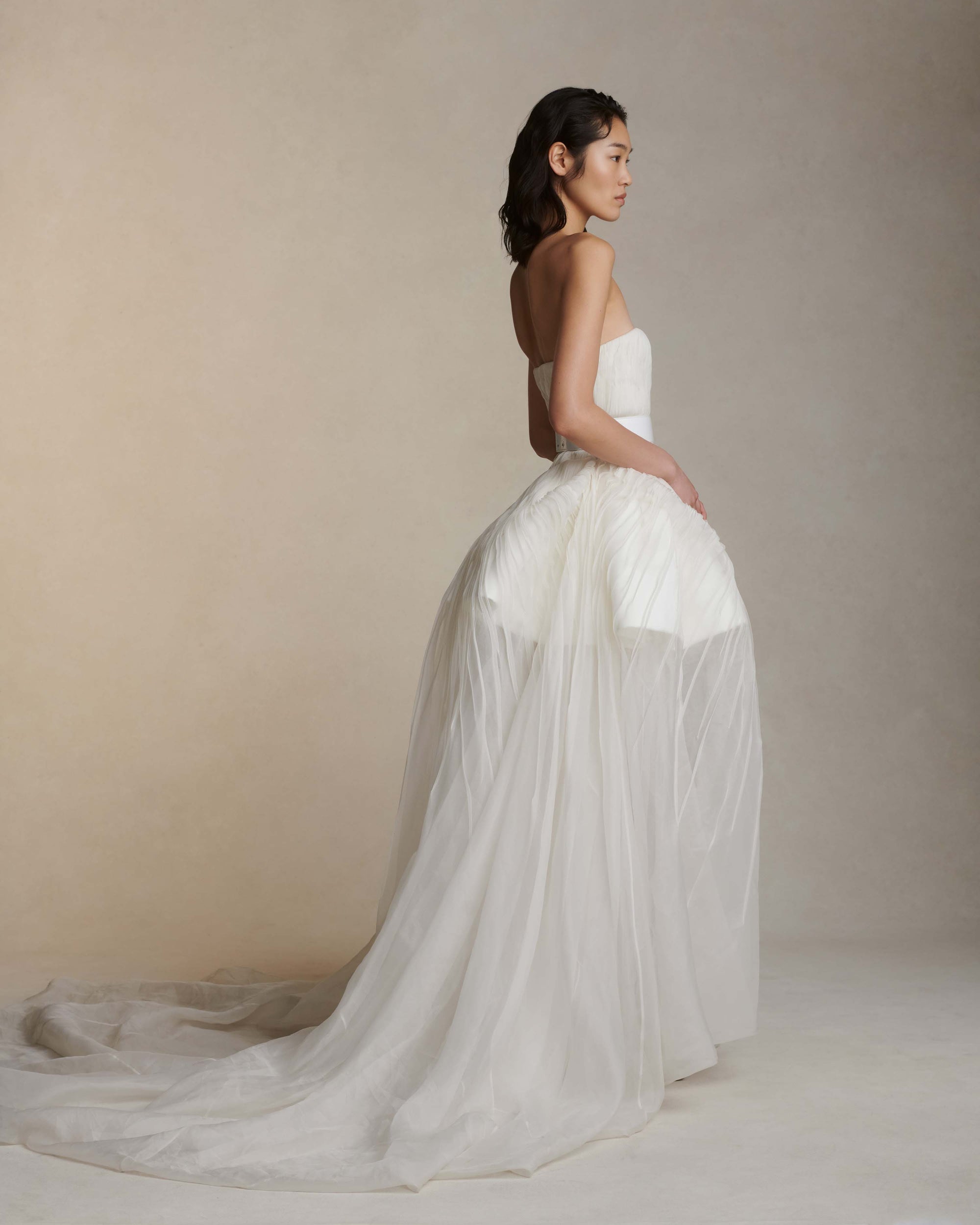 Silk organza strapless translucent ball gown with pintucked bodice. Basque waistline with soft sweetheart neckline. Sheer bubbled high-low skirt with extended train. Internal bustier with side boning and cups, grosgrain belt with 3 hook position. Center back zip close.The belt is sold separately.