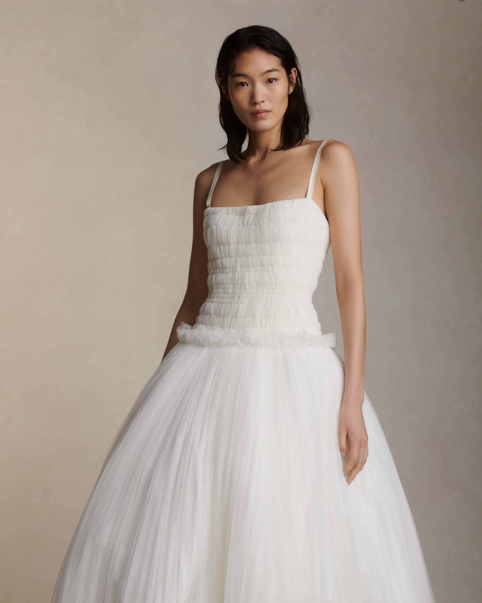 Soft tulle smocked and collapsed ballgown. Tightly gathered pleating along corseted, drop waist bodice. Grosgrain straps connecting to soft v-back. Sunburst pleated soft tulle over crinoline enclosed, bubbled taffeta skirt. Boning through body and center back zip close.