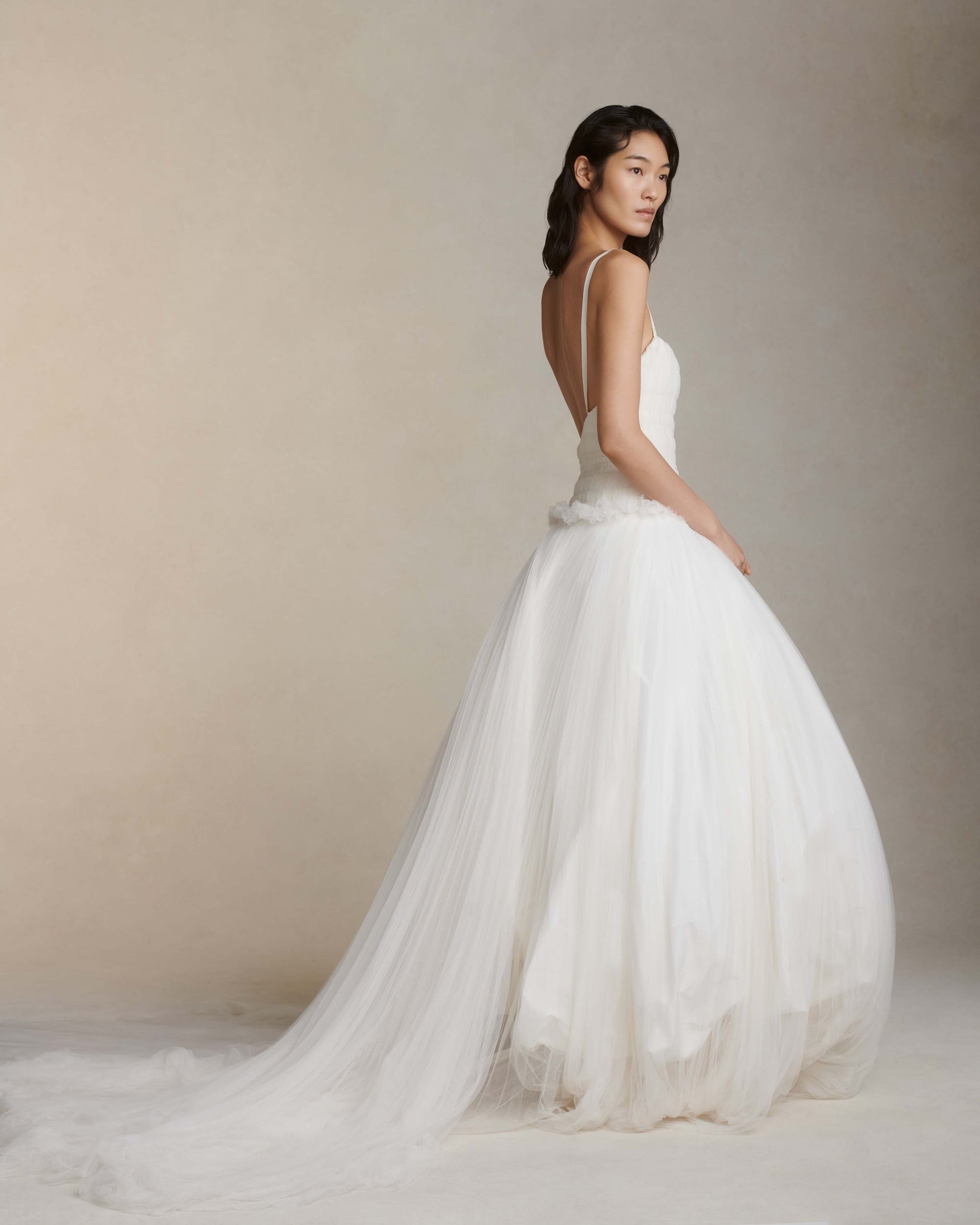 Soft tulle smocked and collapsed ballgown. Tightly gathered pleating along corseted, drop waist bodice. Grosgrain straps connecting to soft v-back. Sunburst pleated soft tulle over crinoline enclosed, bubbled taffeta skirt. Boning through body and center back zip close.