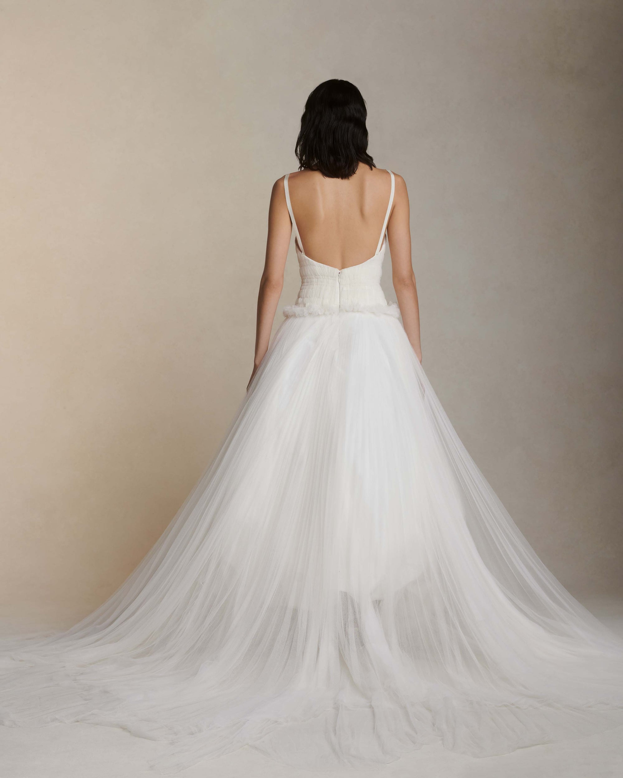 Soft tulle smocked and collapsed ballgown. Tightly gathered pleating along corseted, drop waist bodice. Grosgrain straps connecting to soft v-back. Sunburst pleated soft tulle over crinoline enclosed, bubbled taffeta skirt. Boning through body and center back zip close.