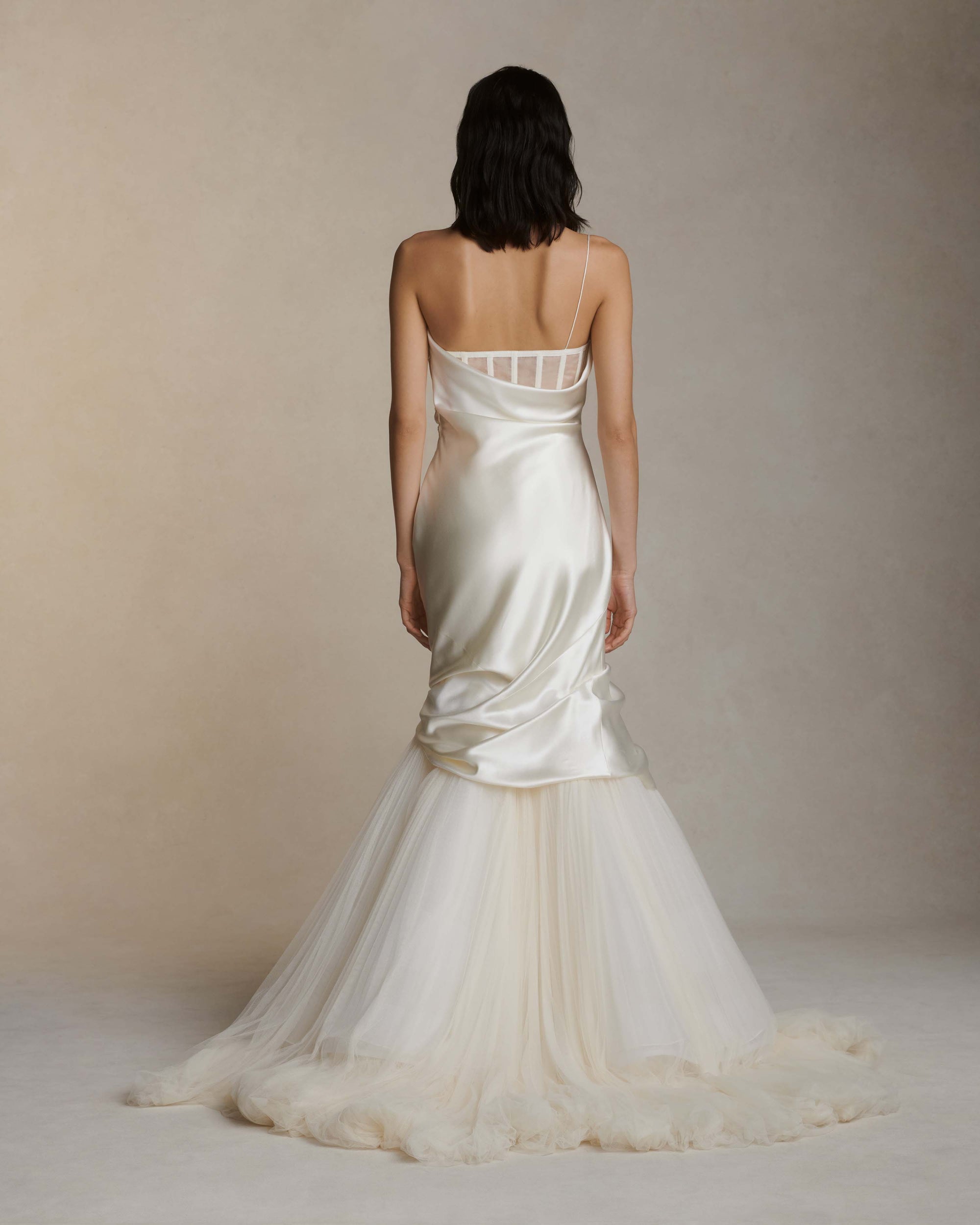 Layered silk wool and soft tulle gown. Fluid draping spills over sunburst pleated tulle skirt with bubble hem. Dipped drape reveals delicate gathered tulle at front neckline and boned organza bustier at back. Soft cups, internal grosgrain waist belt and invisible side zip closure.