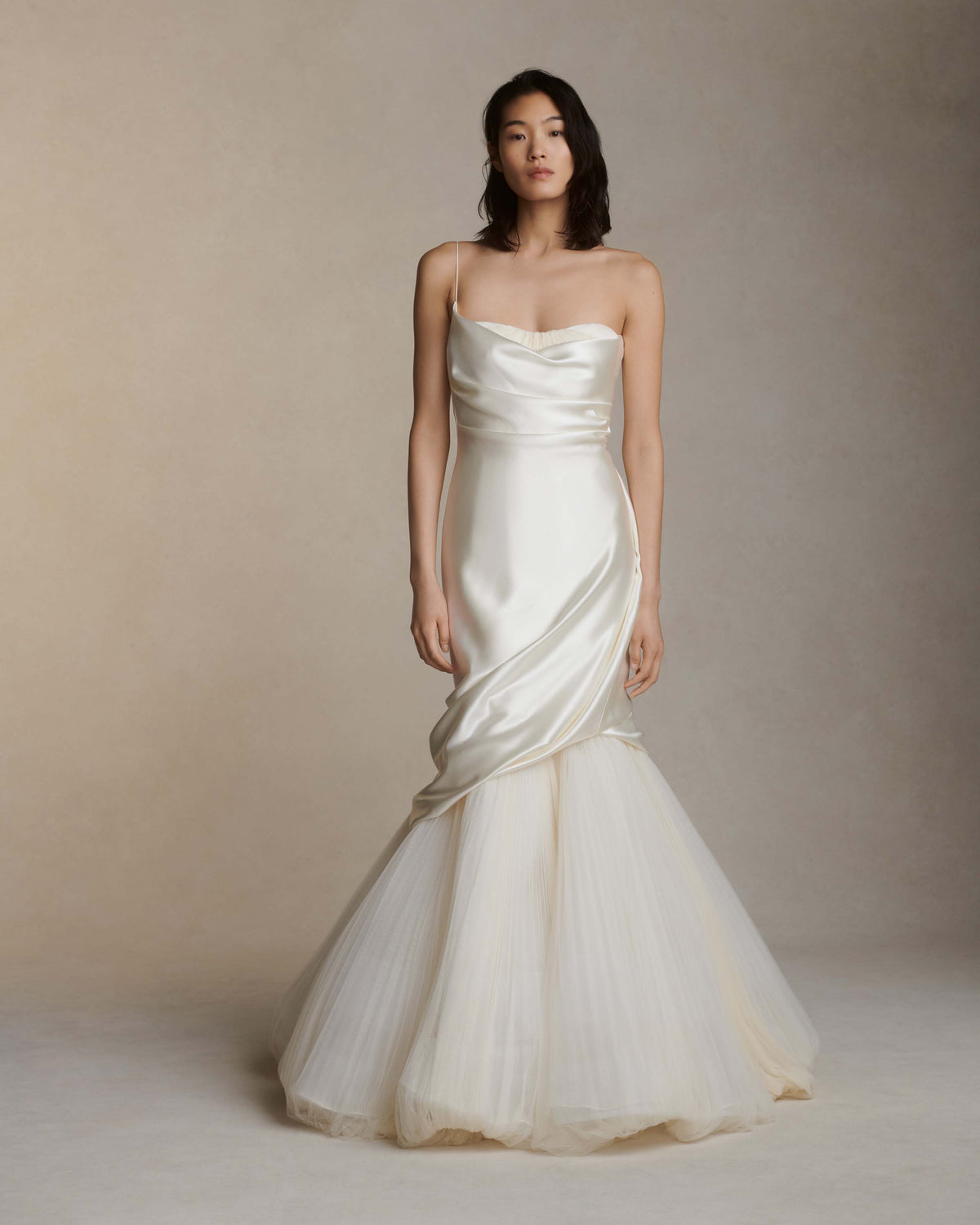 Layered silk wool and soft tulle gown. Fluid draping spills over sunburst pleated tulle skirt with bubble hem. Dipped drape reveals delicate gathered tulle at front neckline and boned organza bustier at back. Soft cups, internal grosgrain waist belt and invisible side zip closure.