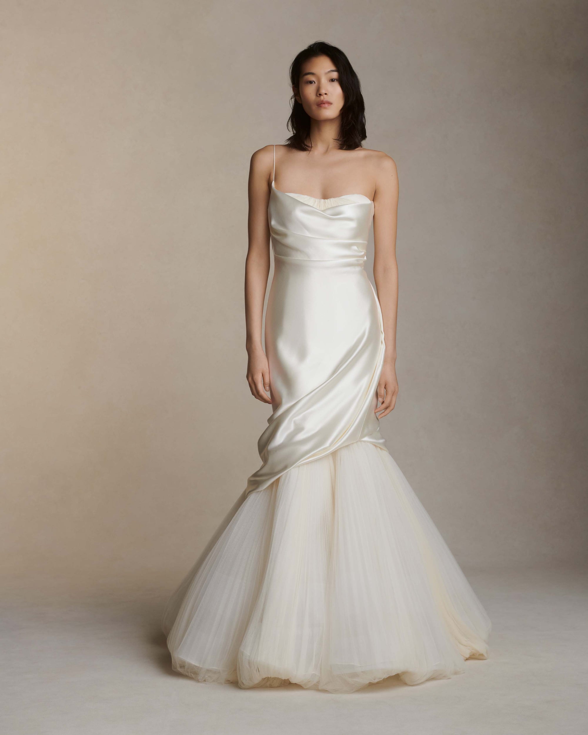 Layered silk wool and soft tulle gown. Fluid draping spills over sunburst pleated tulle skirt with bubble hem. Dipped drape reveals delicate gathered tulle at front neckline and boned organza bustier at back. Soft cups, internal grosgrain waist belt and invisible side zip closure.
