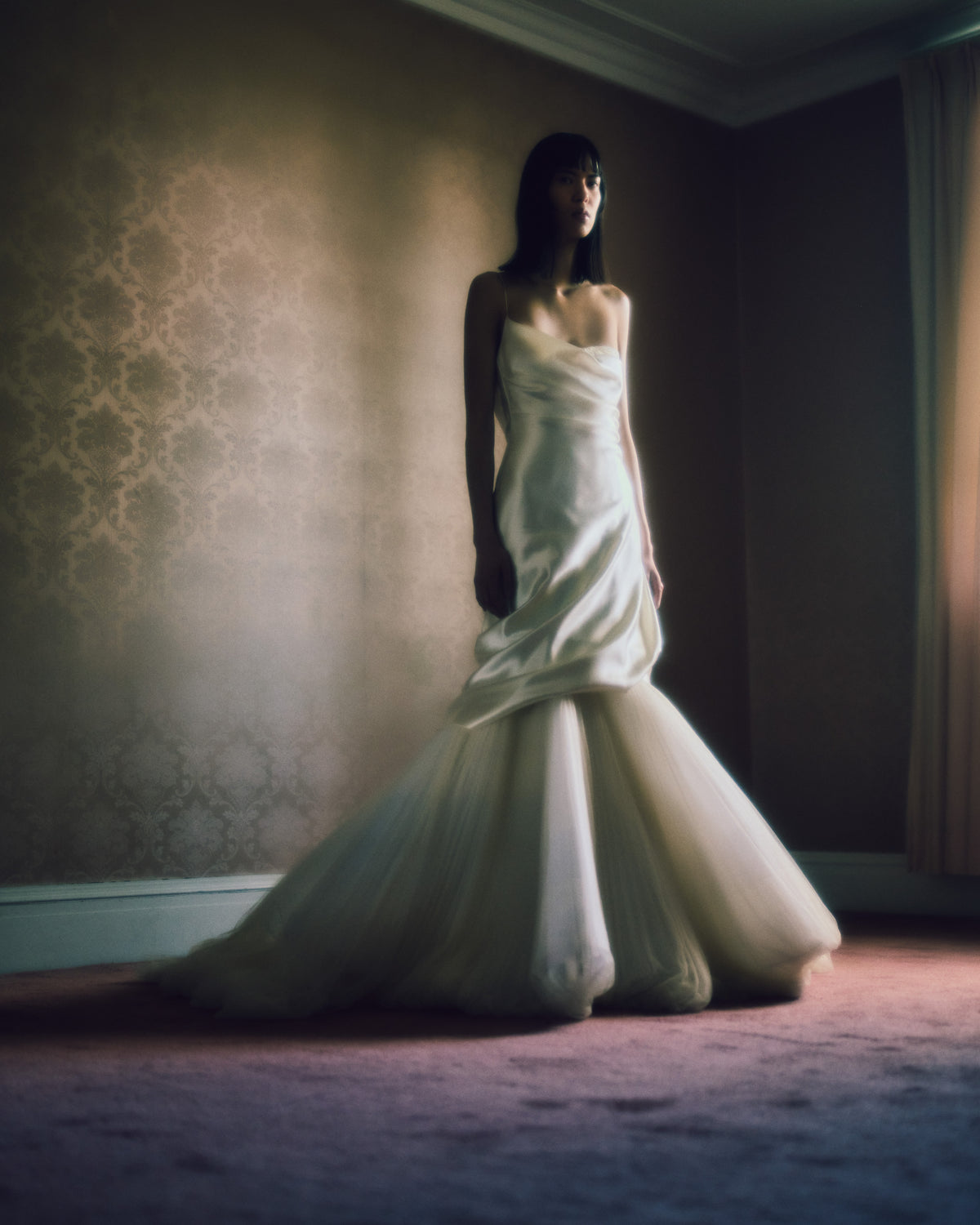 Layered silk wool and soft tulle gown. Fluid draping spills over sunburst pleated tulle skirt with bubble hem. Dipped drape reveals delicate gathered tulle at front neckline and boned organza bustier at back. Soft cups, internal grosgrain waist belt and invisible side zip closure.
