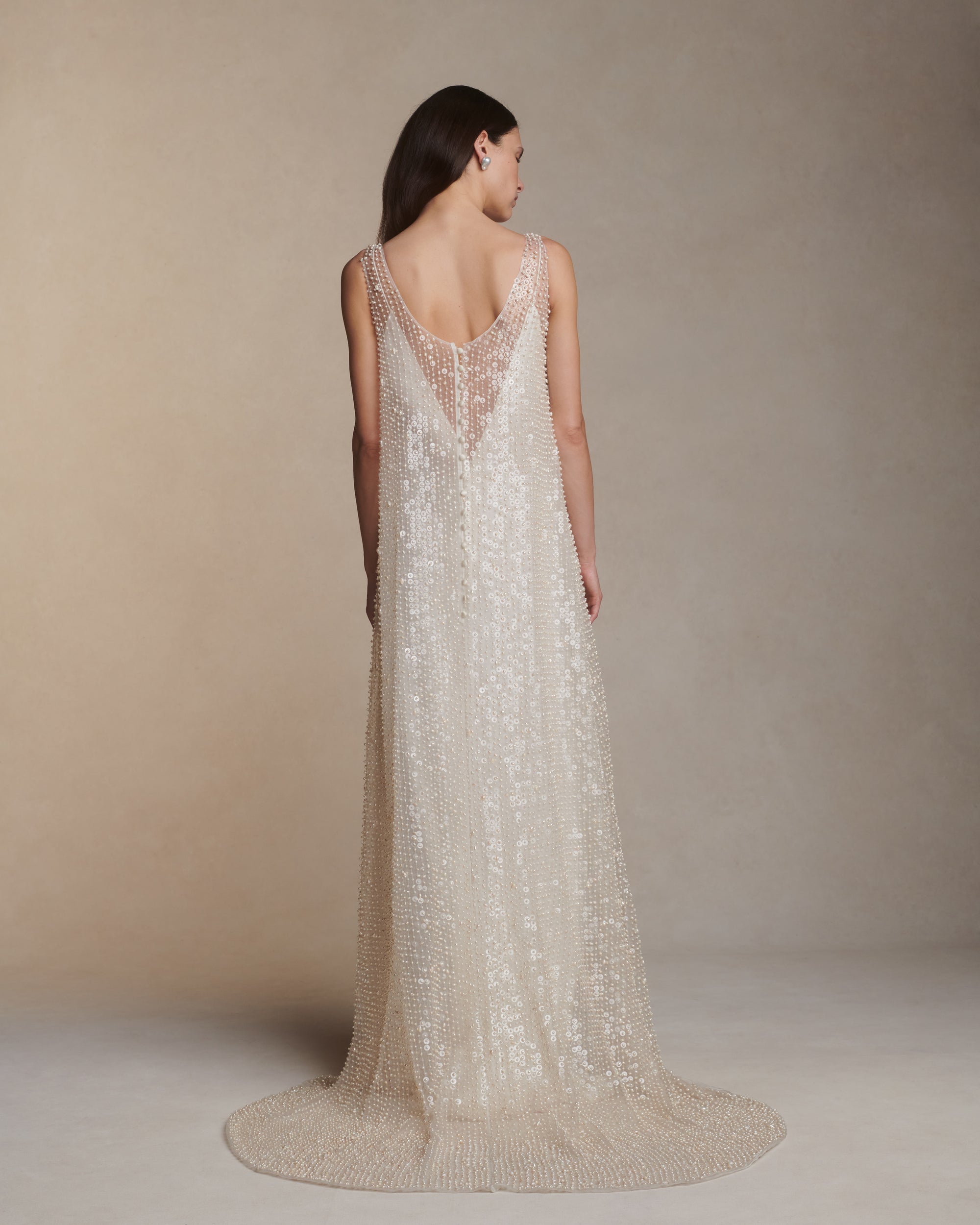Air organza deep V-neck A-line gown hand embroidered with genuine baroque pearls and transparent sequins throughout. Loop and covered button closure at center back. 