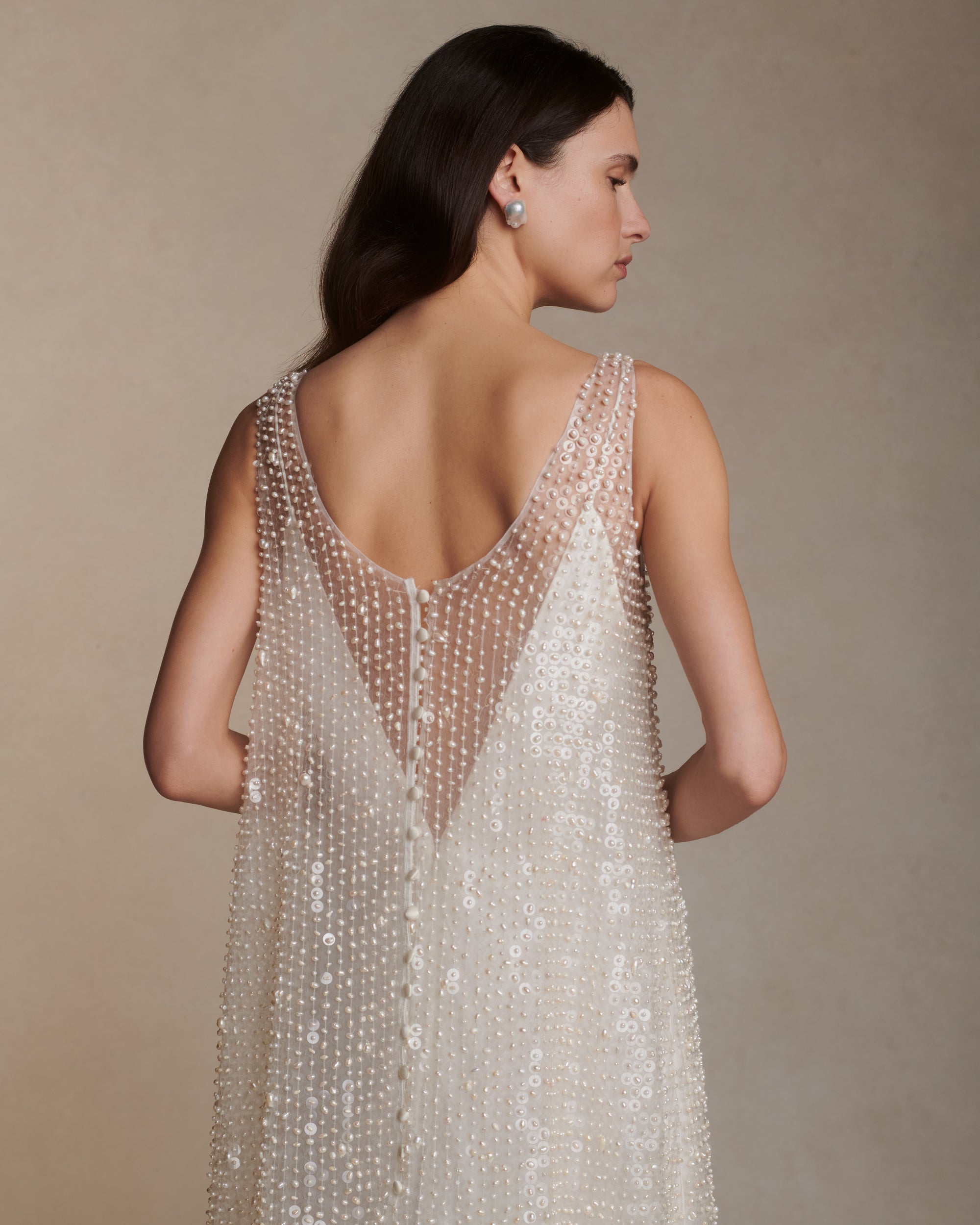 Air organza deep V-neck A-line gown hand embroidered with genuine baroque pearls and transparent sequins throughout. Loop and covered button closure at center back. 