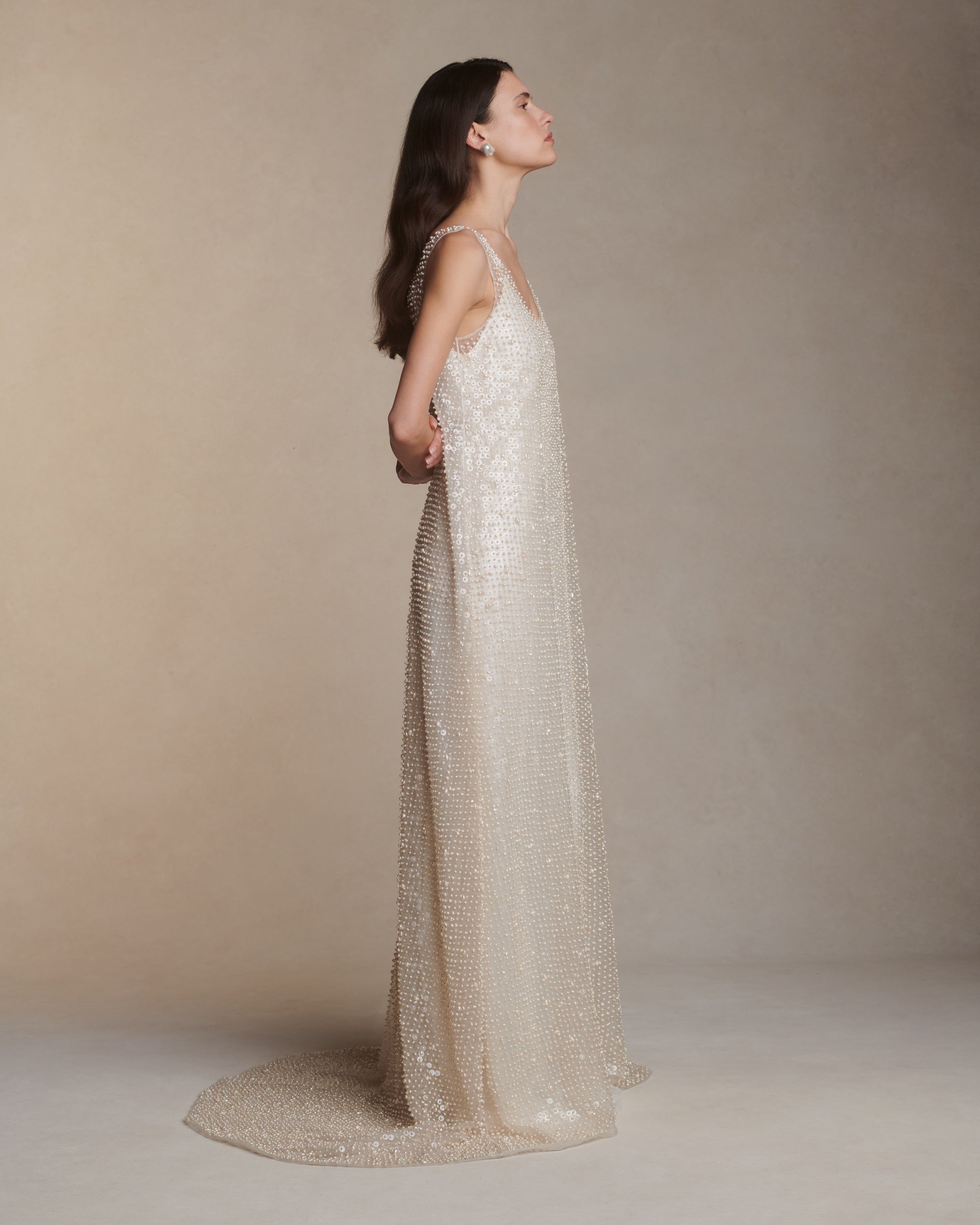 Air organza deep V-neck A-line gown hand embroidered with genuine baroque pearls and transparent sequins throughout. Loop and covered button closure at center back. 