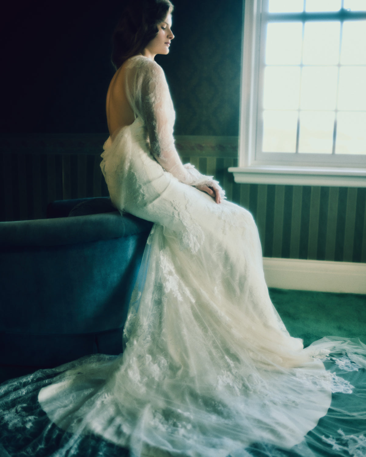 Romantic long sleeve iris lace and soft tulle gown adorned with hand cut chantilly and corded lace appliqués. A diaphanous overlay extends beyond a stretch Cady spaghetti strap foundation into delicate draping across neck and decolletage, spilling into a scarf drape detail at low back. Boned internal bustier, internal grosgrain waist belt and center back zip closure.