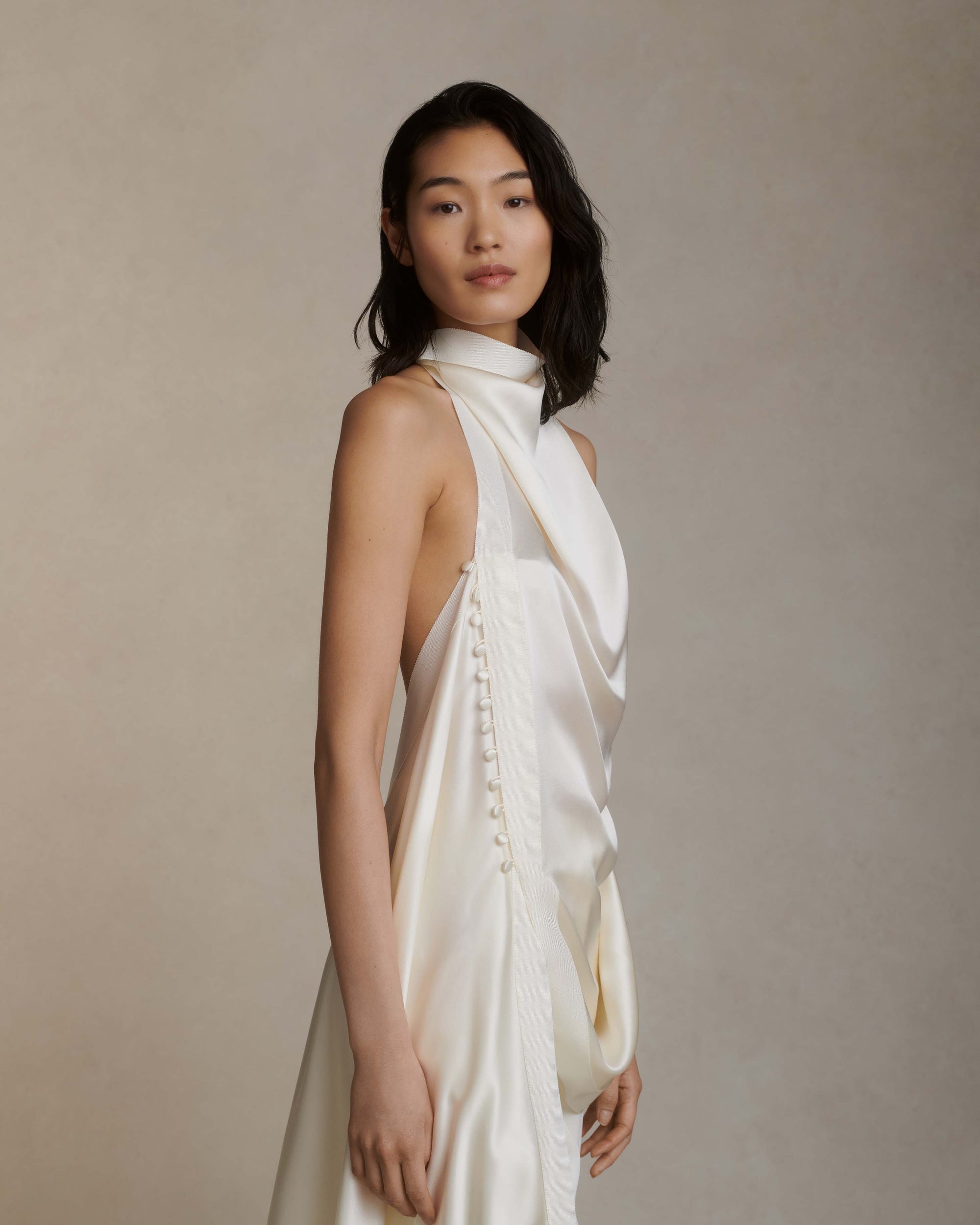 Silk crepe back satin handkerchief top. Grosgrain edging and covered button detailing along side. Optional bustle loop on handkerchief corner hem. Slip on styling with button close at neck.Styled with Miriam pant