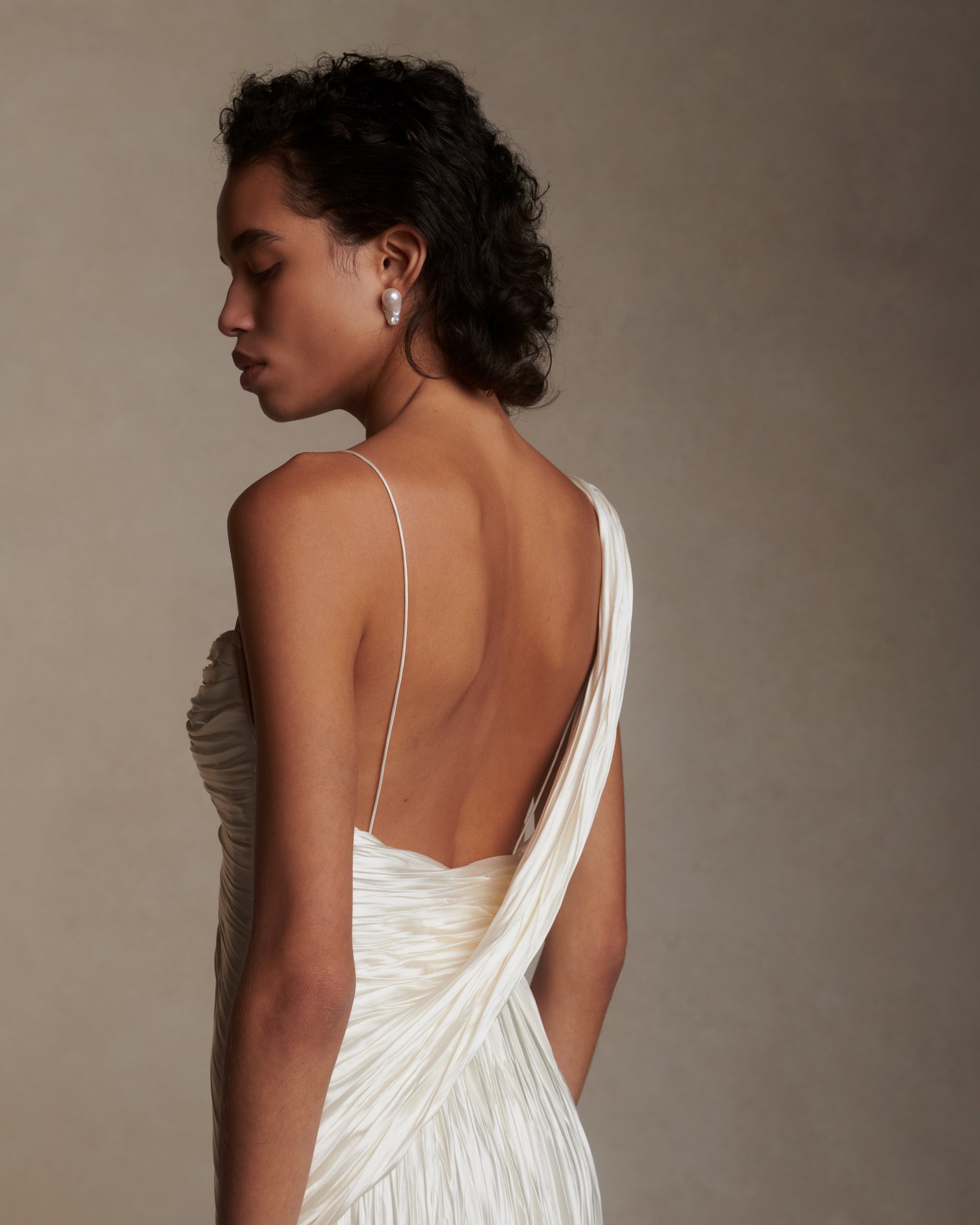 One shoulder pleated and hand crinkled silk wool cocktail length dress with dipped neckline. Asymmetric drape sweeps across front into a delicate twisted back detail. Boned internal bustier with soft cups, internal grosgrain waist belt and side zip closure.