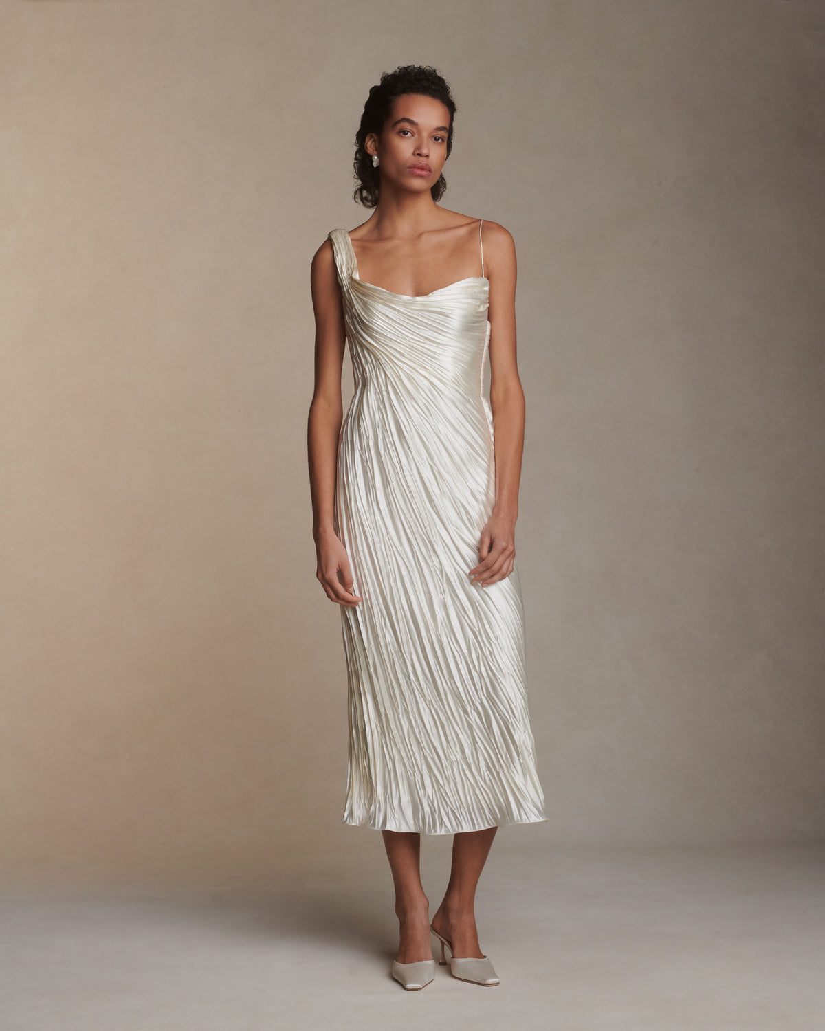 One shoulder pleated and hand crinkled silk wool cocktail length dress with dipped neckline. Asymmetric drape sweeps across front into a delicate twisted back detail. Boned internal bustier with soft cups, internal grosgrain waist belt and side zip closure.