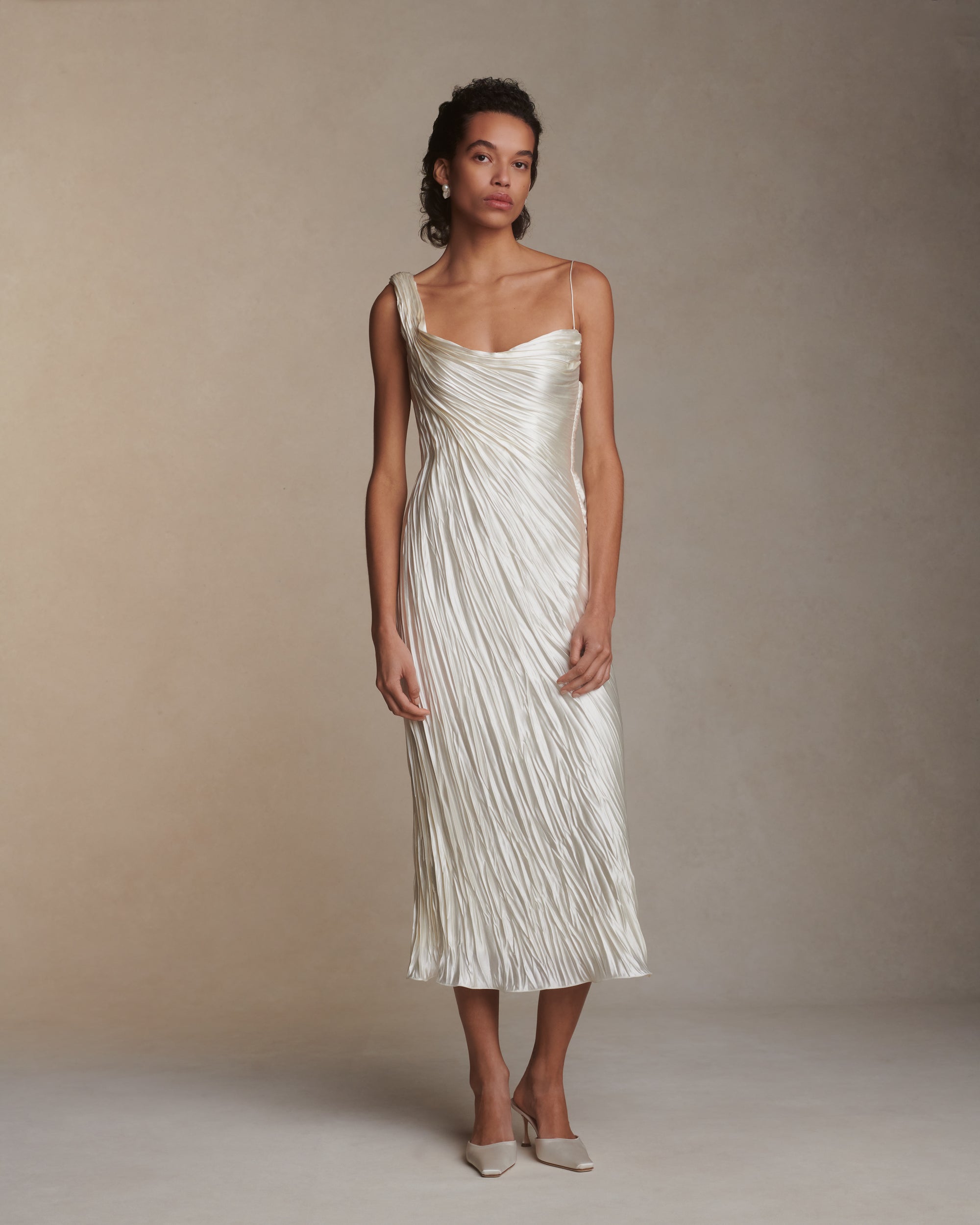 One shoulder pleated and hand crinkled silk wool cocktail length dress with dipped neckline. Asymmetric drape sweeps across front into a delicate twisted back detail. Boned internal bustier with soft cups, internal grosgrain waist belt and side zip closure.