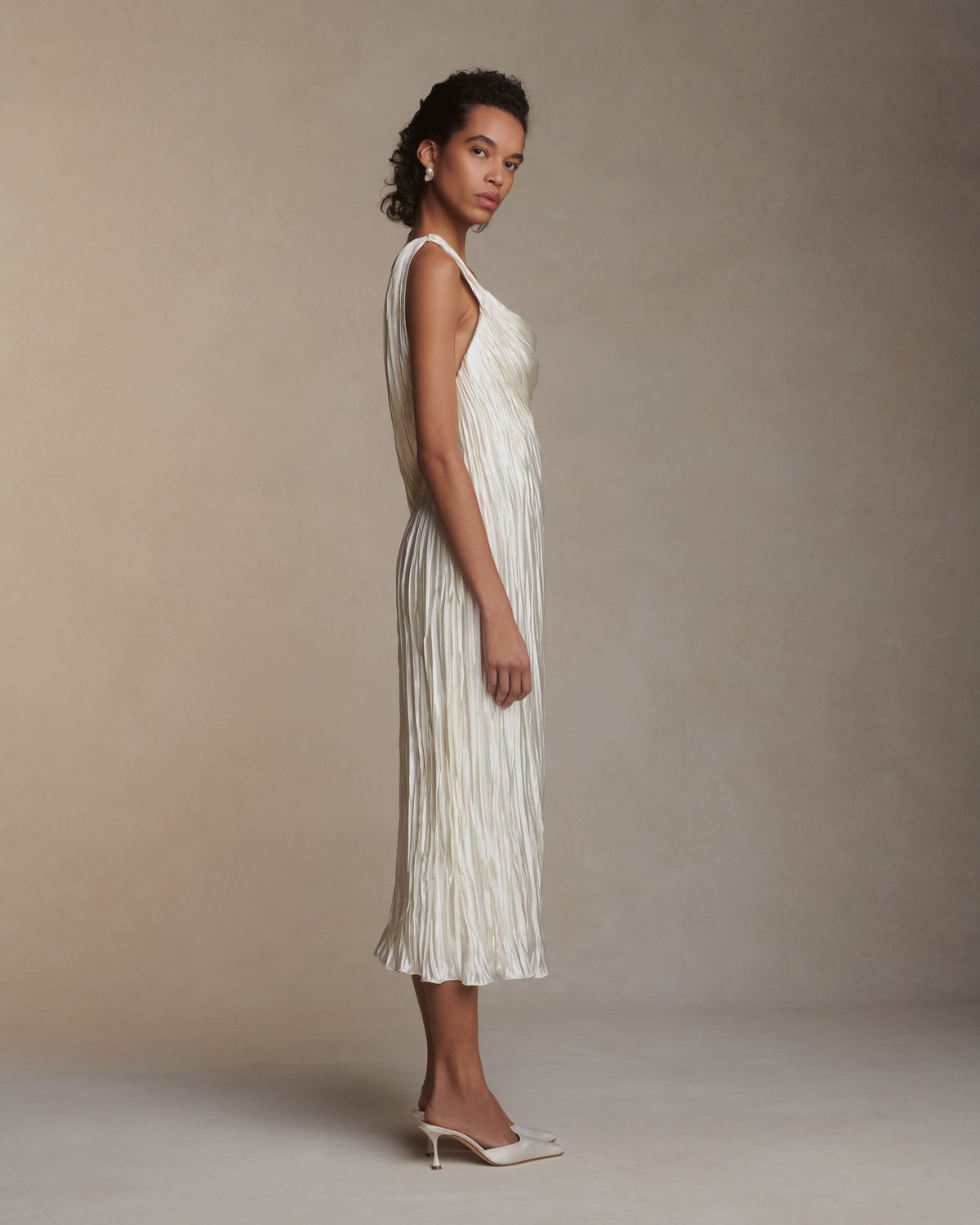 One shoulder pleated and hand crinkled silk wool cocktail length dress with dipped neckline. Asymmetric drape sweeps across front into a delicate twisted back detail. Boned internal bustier with soft cups, internal grosgrain waist belt and side zip closure.