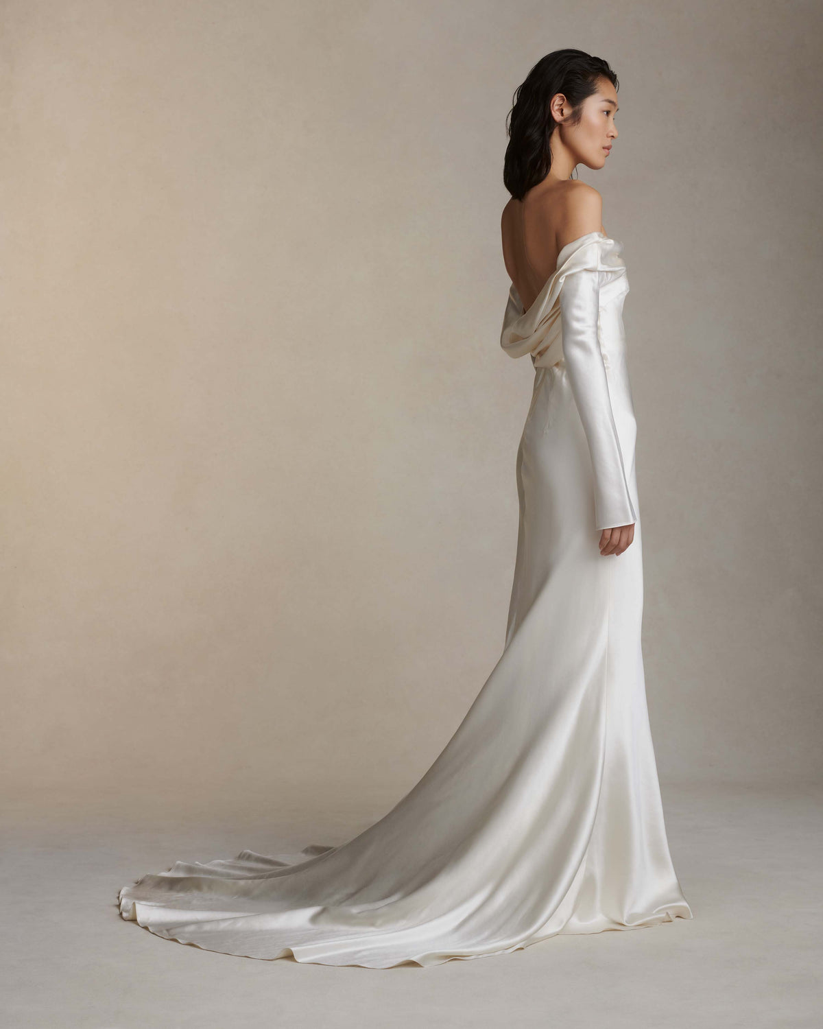 Wilted, long sleeve off the shoulder bias cut silk wool gown with criss-cross draping detail across low back. Darts at bust for shaping and 5 inch slit opening at inner wrist. Boned internal bustier with grosgrain, three closure position belt, wireless cups, and center back external zip. Fully lined skirt.