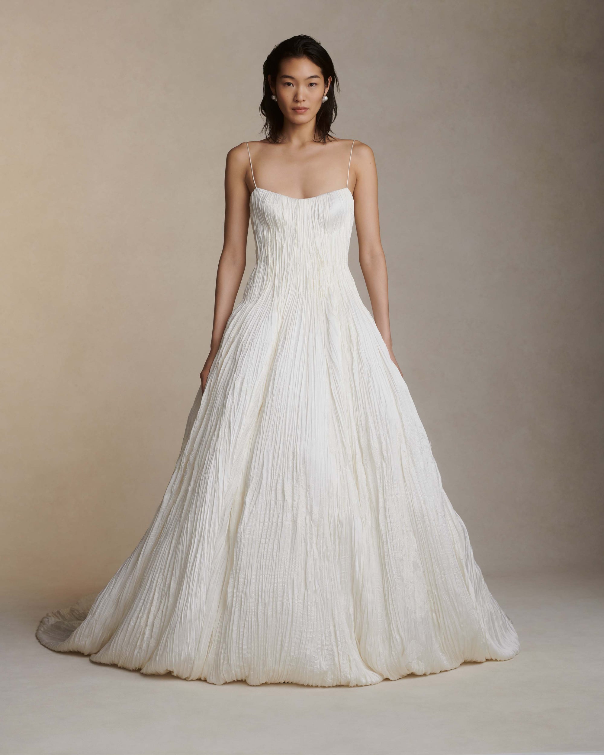 Hand crinkled and sunburst pleated satin gown with delicate spaghetti straps, dipped neckline, and dramatic bubbled skirt and train. Soft internal cups, boning, internal waist belt, invisible center back zip.