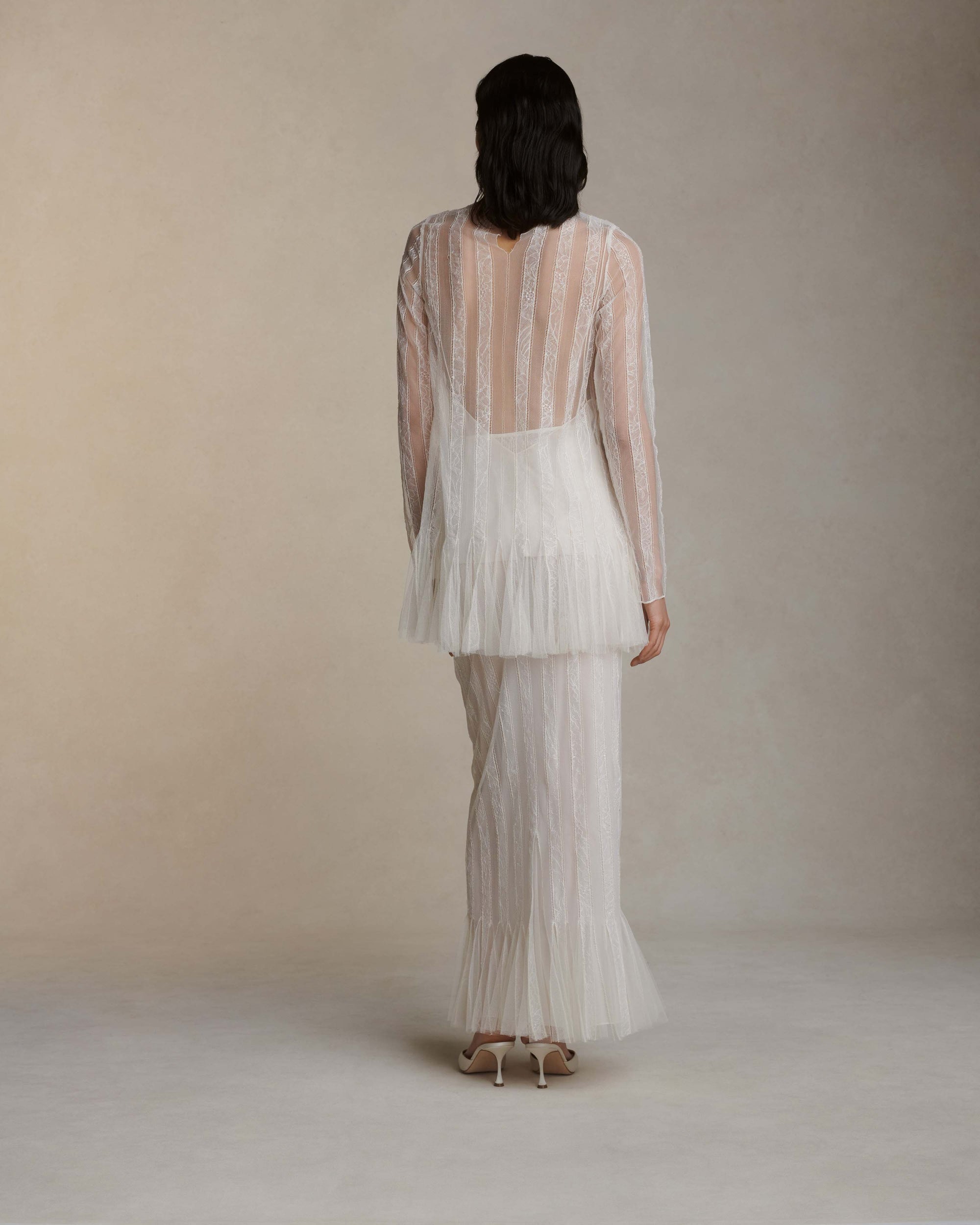 Long sleeve picot lace mini dress with hand appliqued floral chantilly lace stripes and soft tulle godets at hem. Foldover high neck with purl edge stitch detail. Nude slip lining, covered button and loop closure at center back neck.Styled with Henri