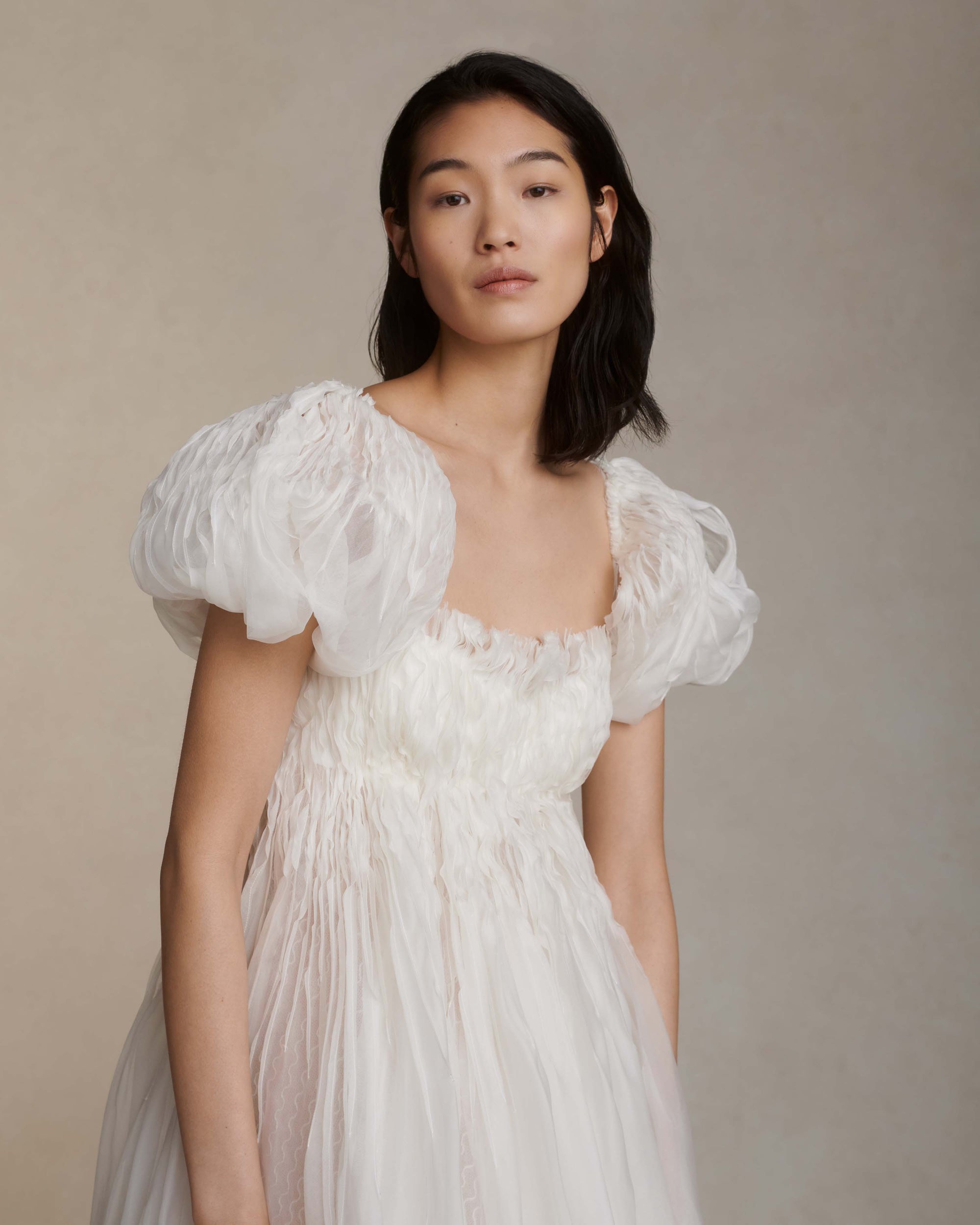 Darted and hand twisted organza ballgown with wave lace underlay. Puffed, tacked cap sleeve framing squared, empire neckline. Soft internal corset free of boning and wires with center back zipper. Nude georgette mini lining with can can and horsehair for shape and structure. 