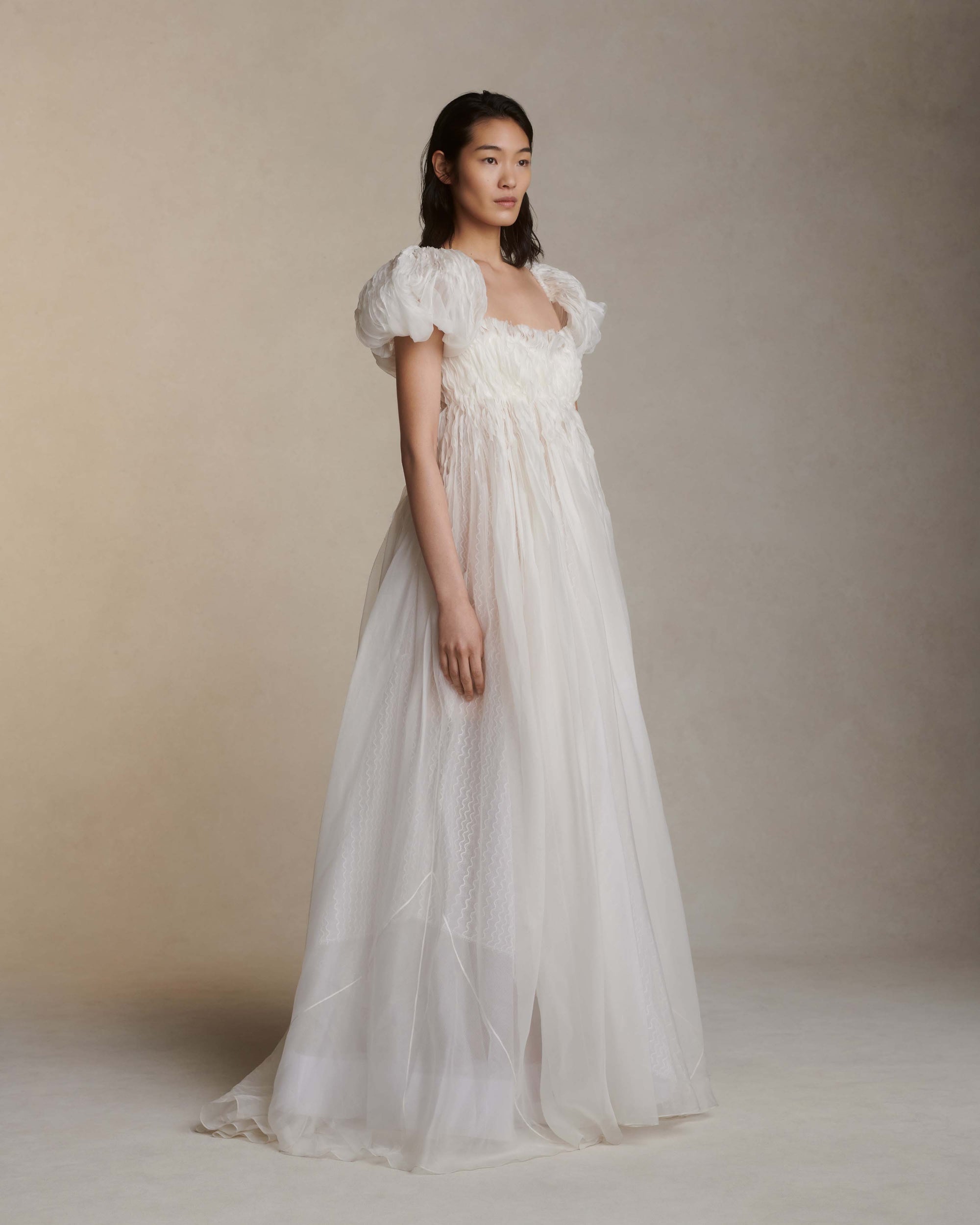 Darted and hand twisted organza ballgown with wave lace underlay. Puffed, tacked cap sleeve framing squared, empire neckline. Soft internal corset free of boning and wires with center back zipper. Nude georgette mini lining with can can and horsehair for shape and structure. 