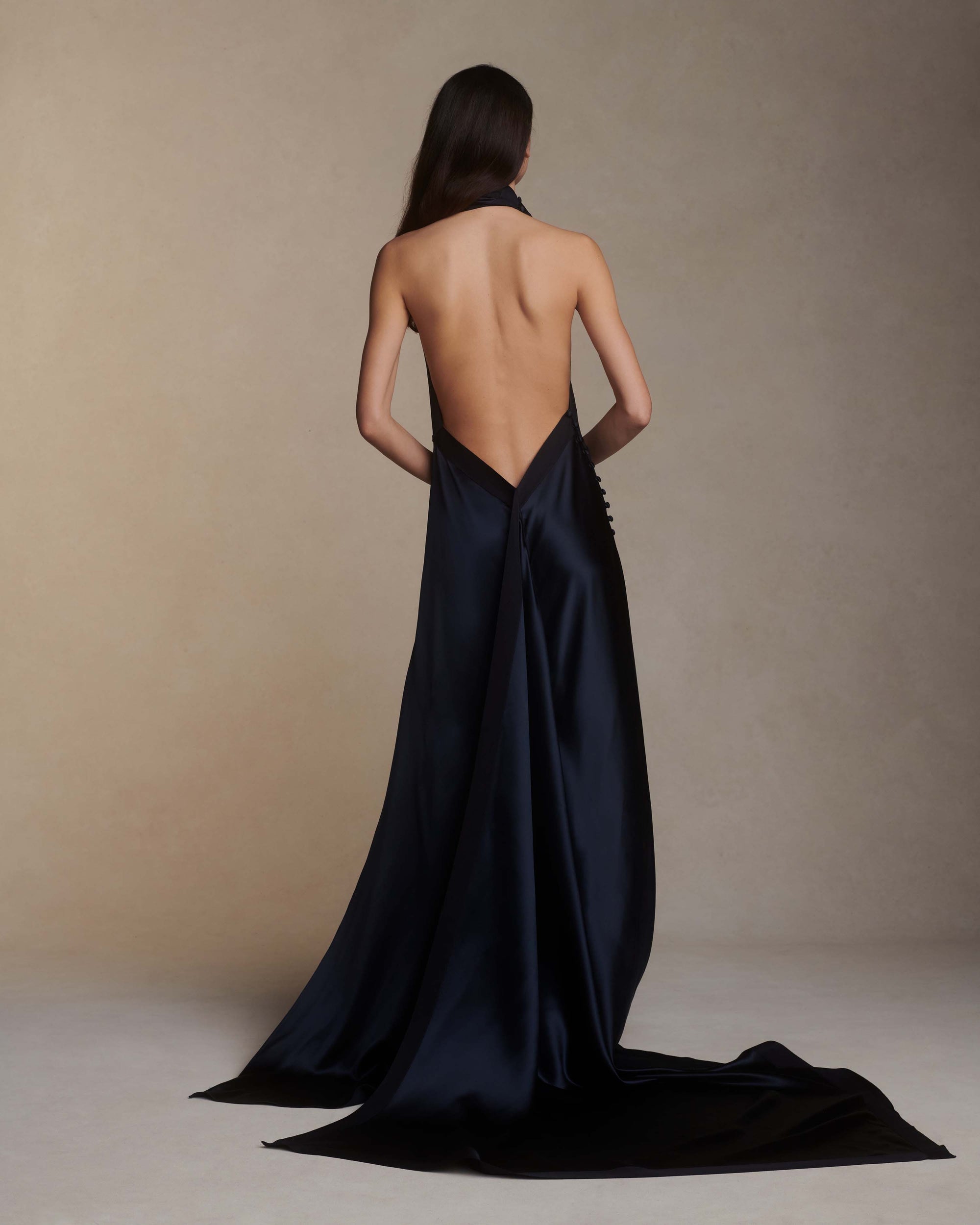 Silk crepe back satin handkerchief gown. Grosgrain edging and covered button detailing along side hip. Optional bustle loop on handkerchief corner hem. Slip on styling with button close at neck.