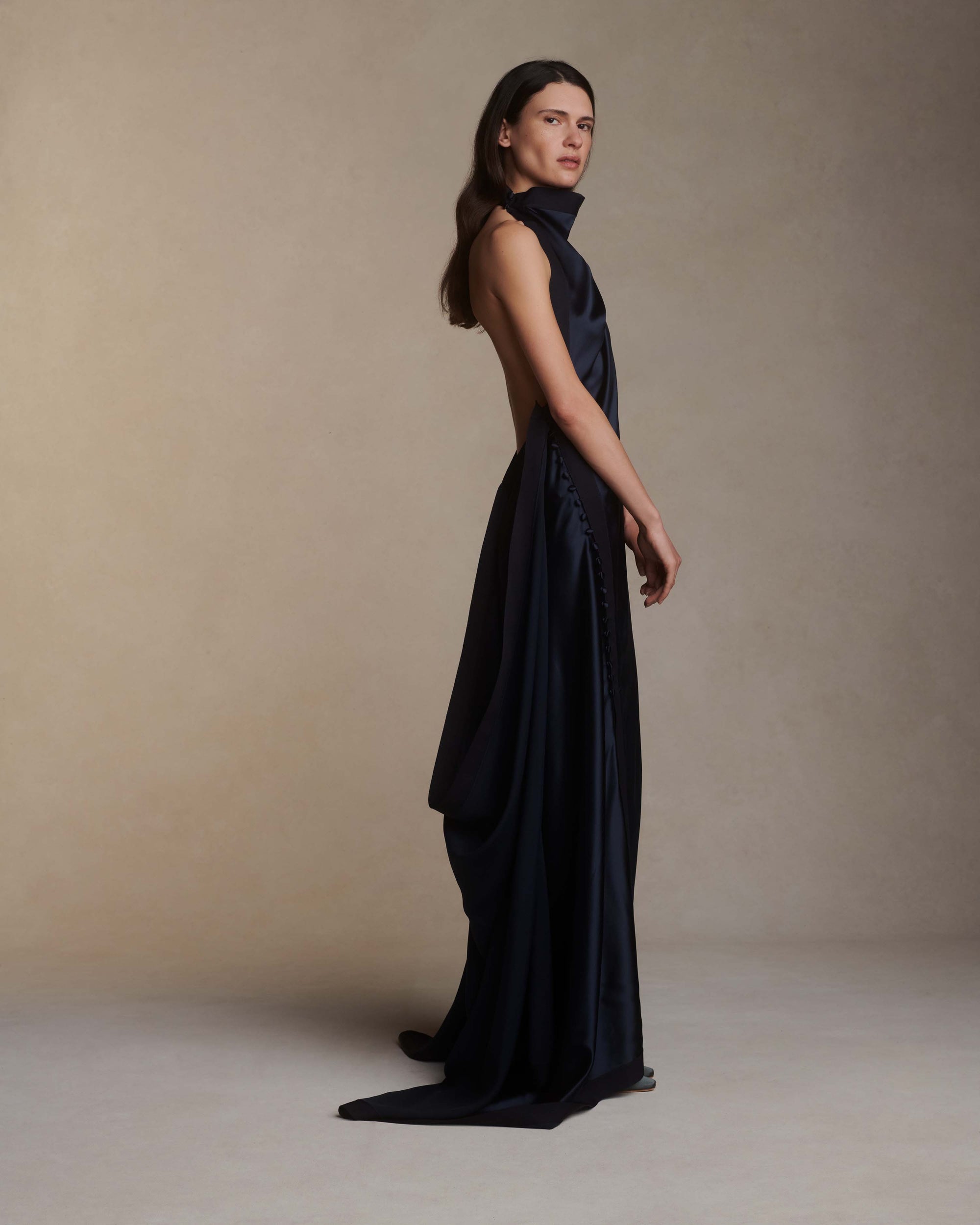 Silk crepe back satin handkerchief gown. Grosgrain edging and covered button detailing along side hip. Optional bustle loop on handkerchief corner hem. Slip on styling with button close at neck.