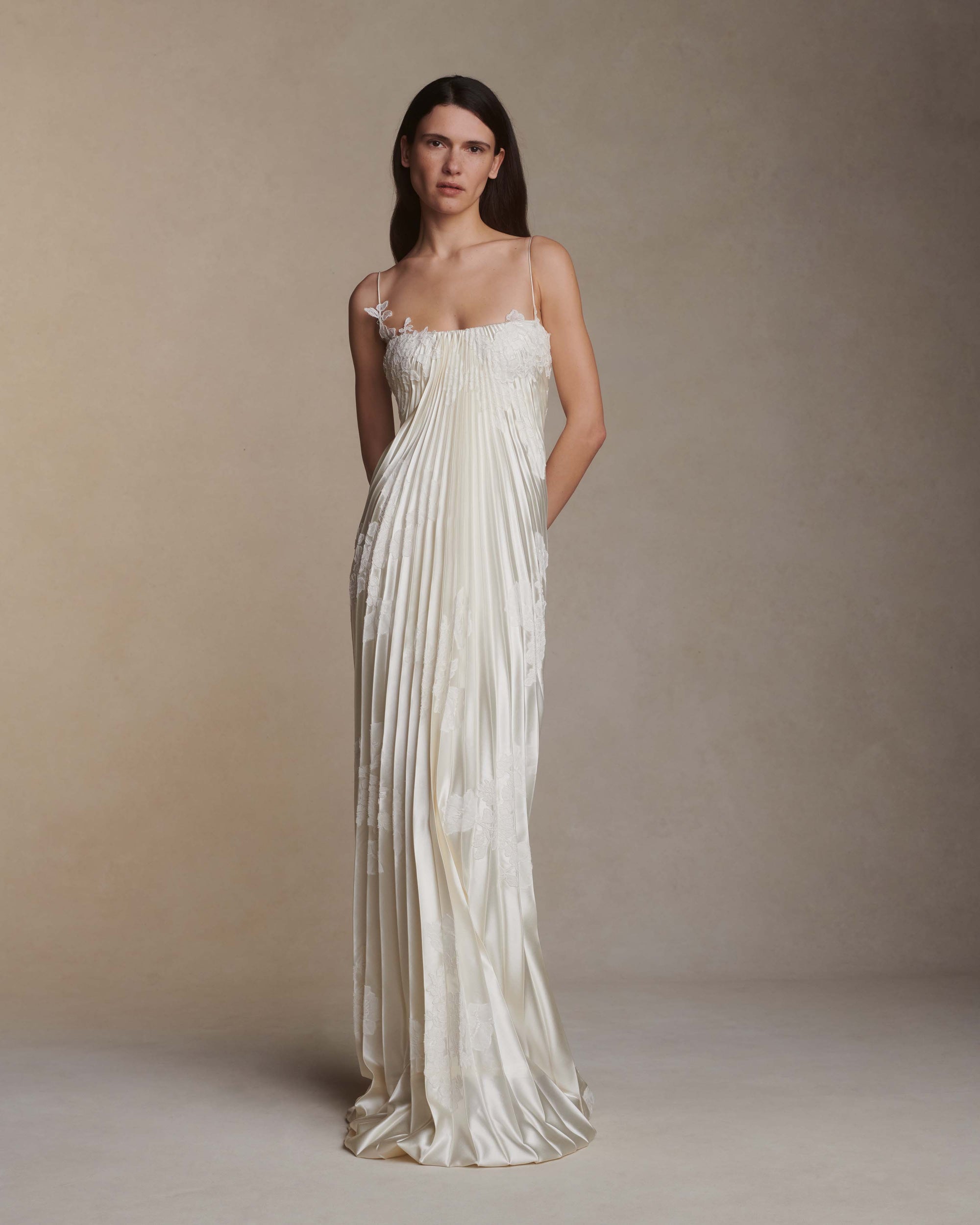 Pleated silk wool column gown with hand appliqué Chantilly and corded lace. Detachable Watteau train pouring down center back. Soft internal bustier with side boning, cups, and grosgrain belt with 3 hook position. Low center back zip, hook and eye closure.