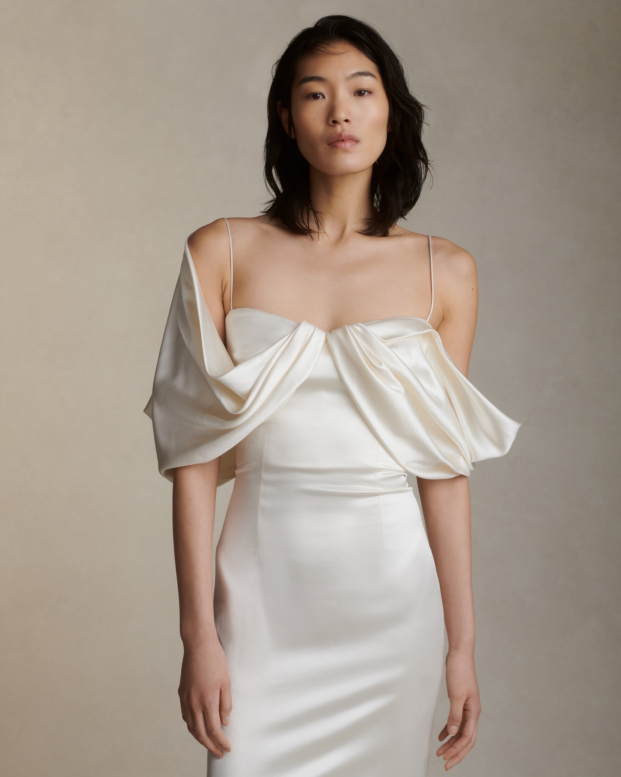 Silk wool gown with asymmetrical swagged sleeve. Detachable watteau train pouring down center back. External darts for shaping and spaghetti straps for contrast. Soft internal bustier with side boning, cups, and grosgrain belt with 3 hook position. Low center back zip, hook and eye closure.