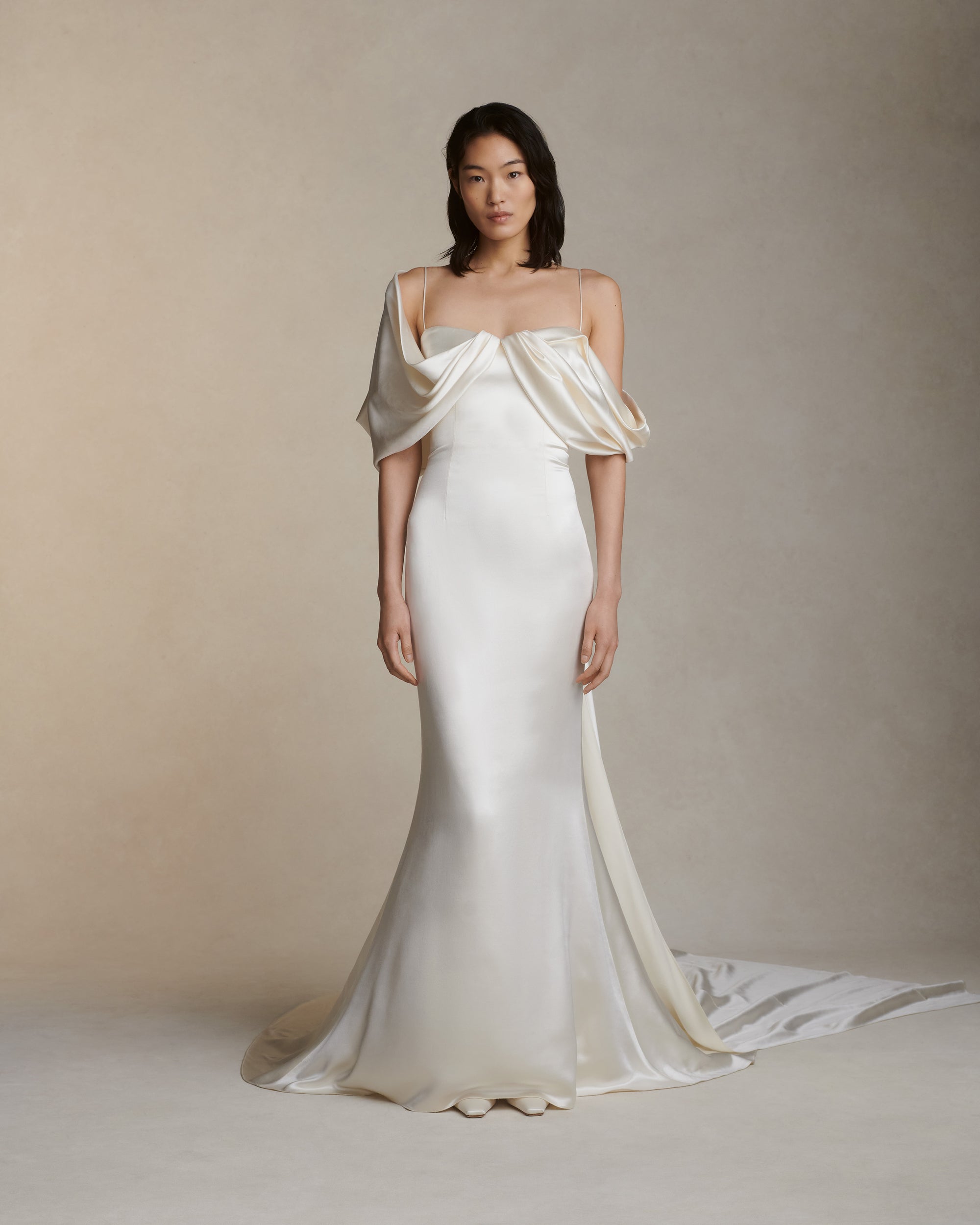 Silk wool gown with asymmetrical swagged sleeve. Detachable watteau train pouring down center back. External darts for shaping and spaghetti straps for contrast. Soft internal bustier with side boning, cups, and grosgrain belt with 3 hook position. Low center back zip, hook and eye closure.