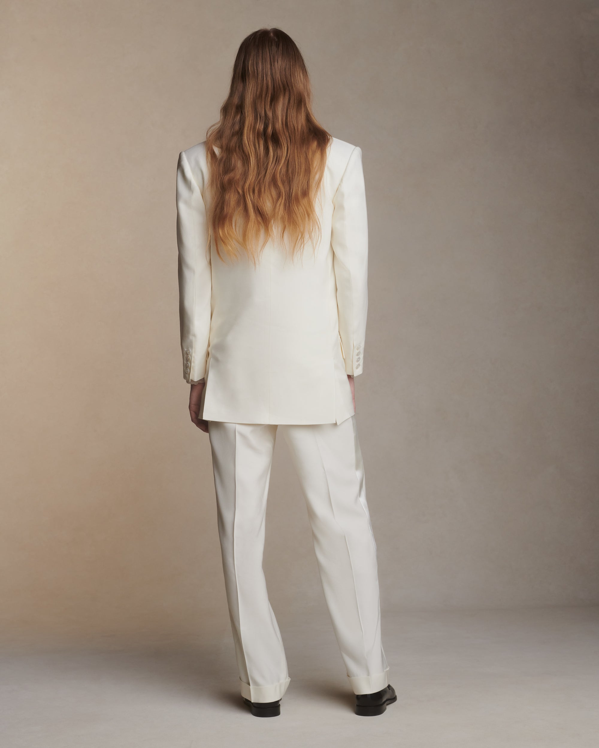 Matte silk wool double breasted jacket with luminous silk wool peaked lapel. Two welt pockets at front and double vented back. Ivory shell buttons at center front and sleeve opening.